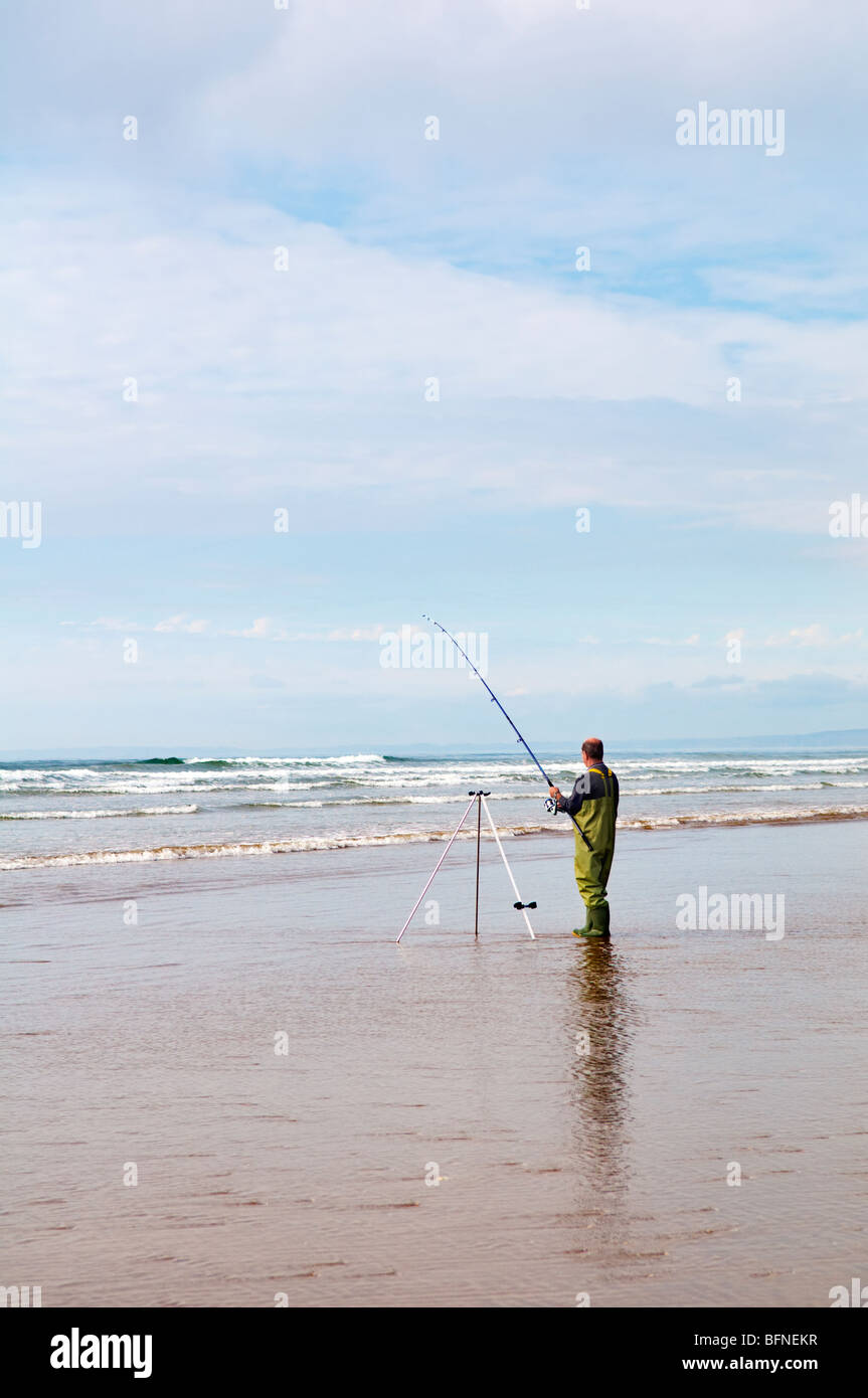 Man sea fishing at Pembrey sands beach Mid Wales on bright day Stock Photo