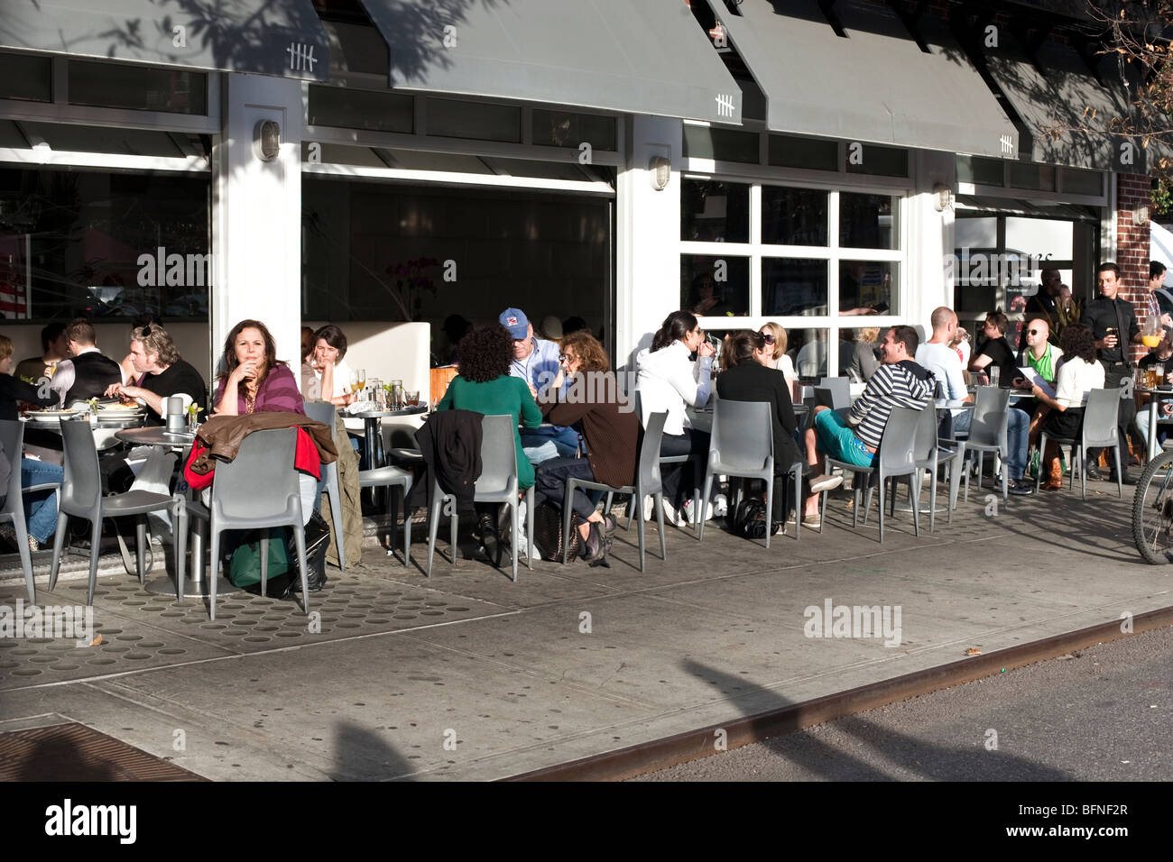varied group New Yorkers eating Sunday brunch at outdoor tables seating