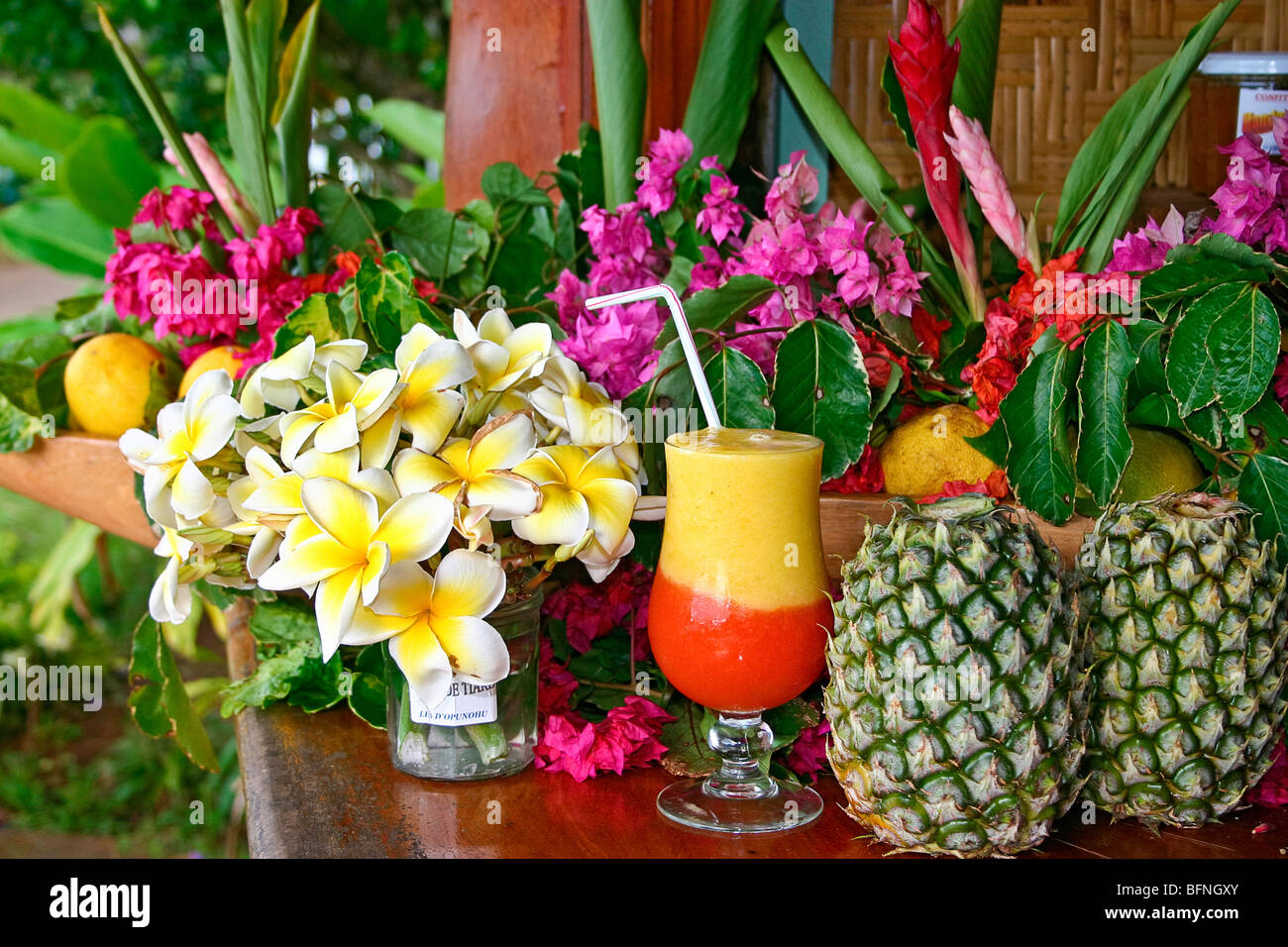 Pineapple and papaya drink surounded by tropical flowers and fresh