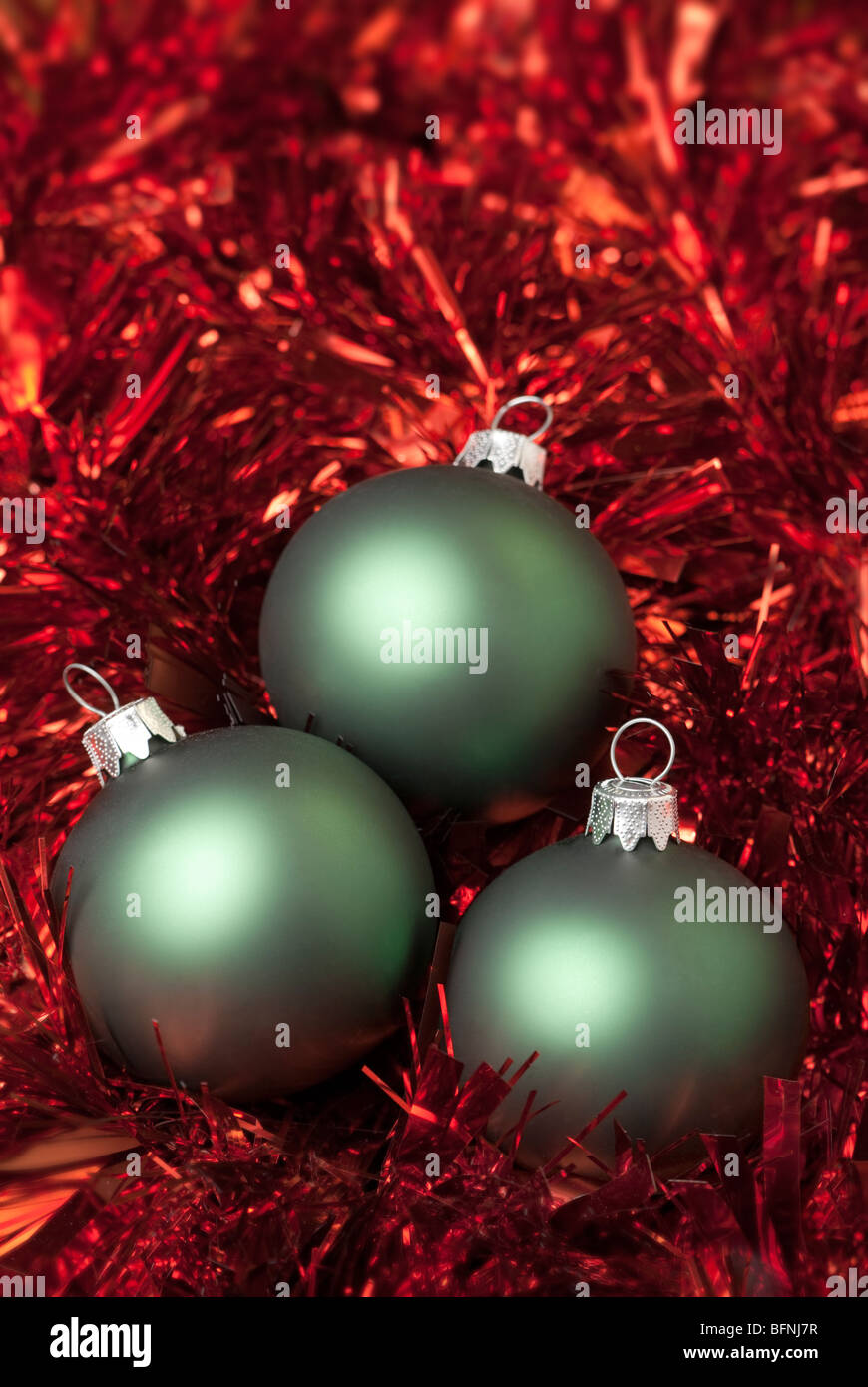 Green christmas ball on the red tinsel. aRGB. Stock Photo