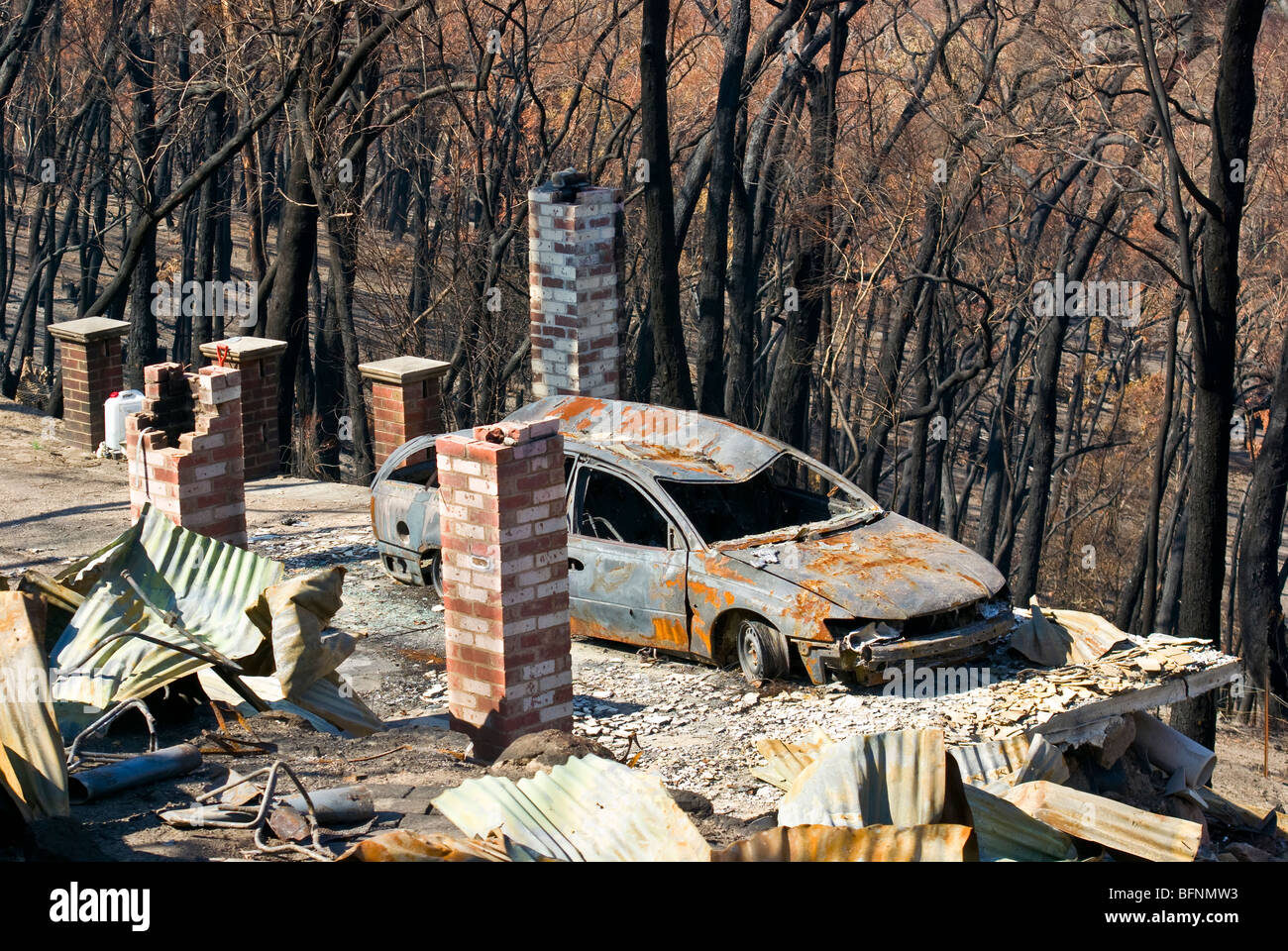 The passing of a bushfire leaves the charred remains of a home and car Stock Photo