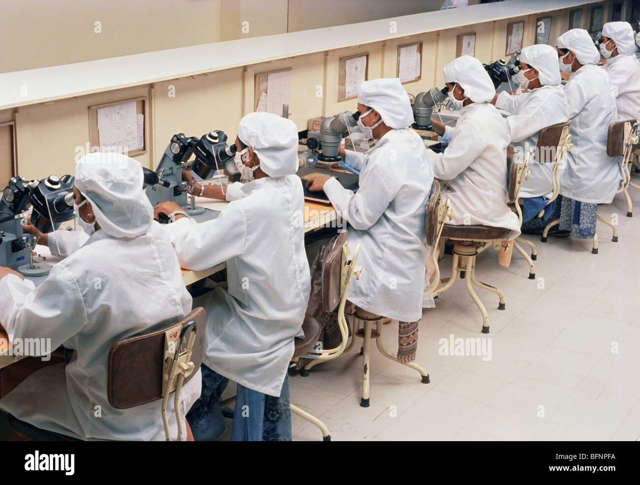 workers looking through microscopes Stock Photo