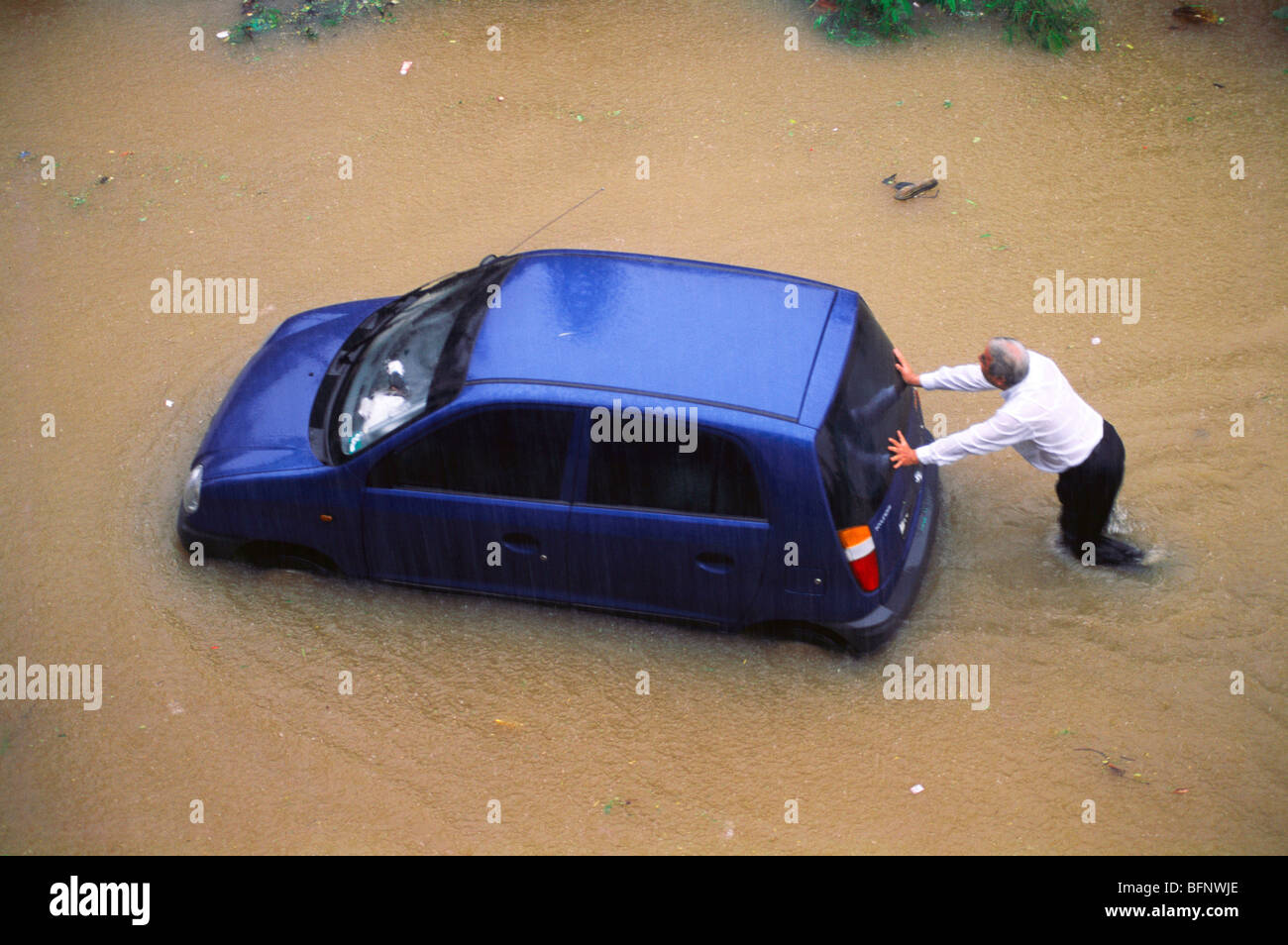 Man pushing car on flooded road in monsoon ; Bombay Mumbai ; Maharashtra ; India ; asia Stock Photo