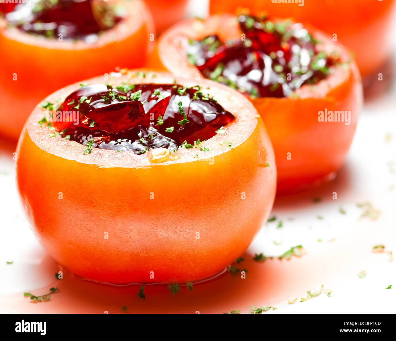 Stuffed tomatoes sprinkled with small cut green herbs. Stock Photo