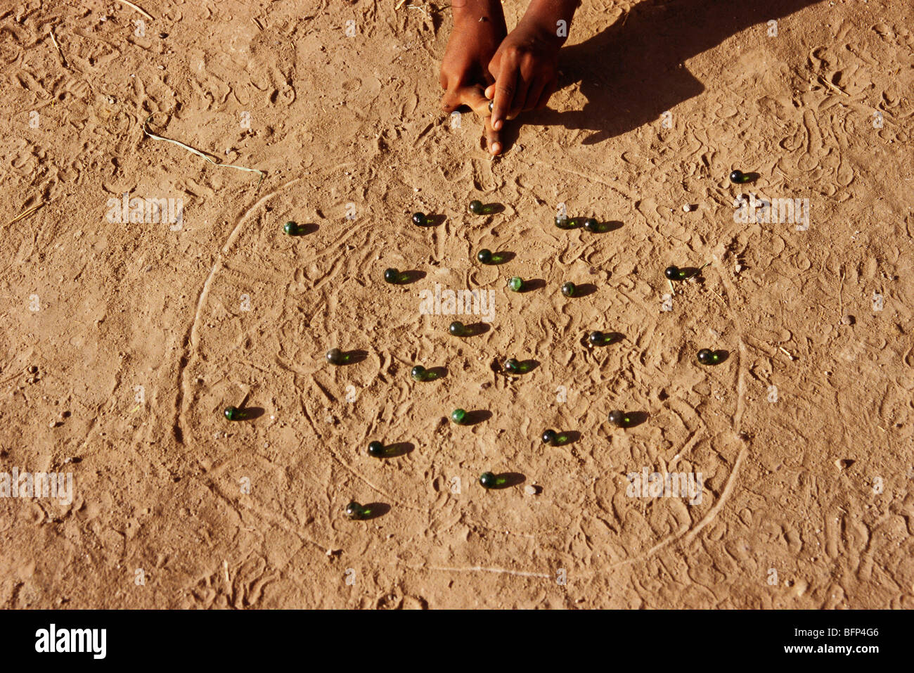 Indian rural boy child playing game of marbles ; Sangli ; Maharashtra