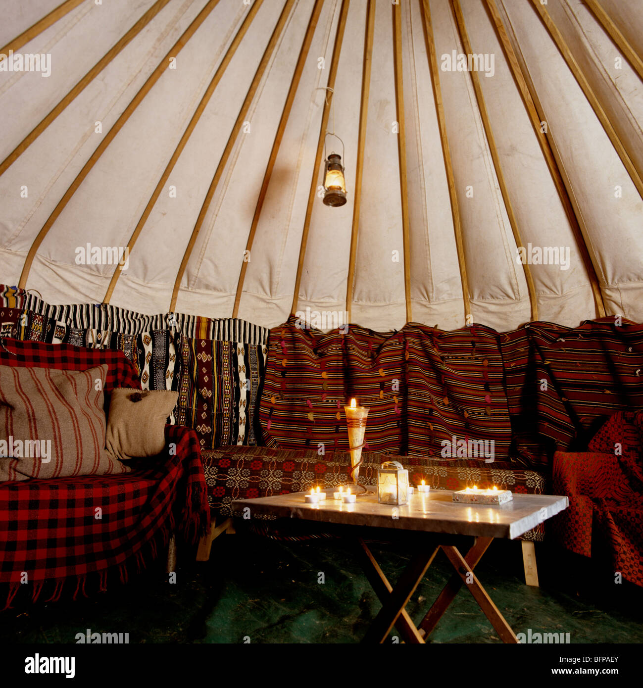 Interior of a yurt / ger lit by candles and lanterns and furnished with Moroccan textiles Stock Photo