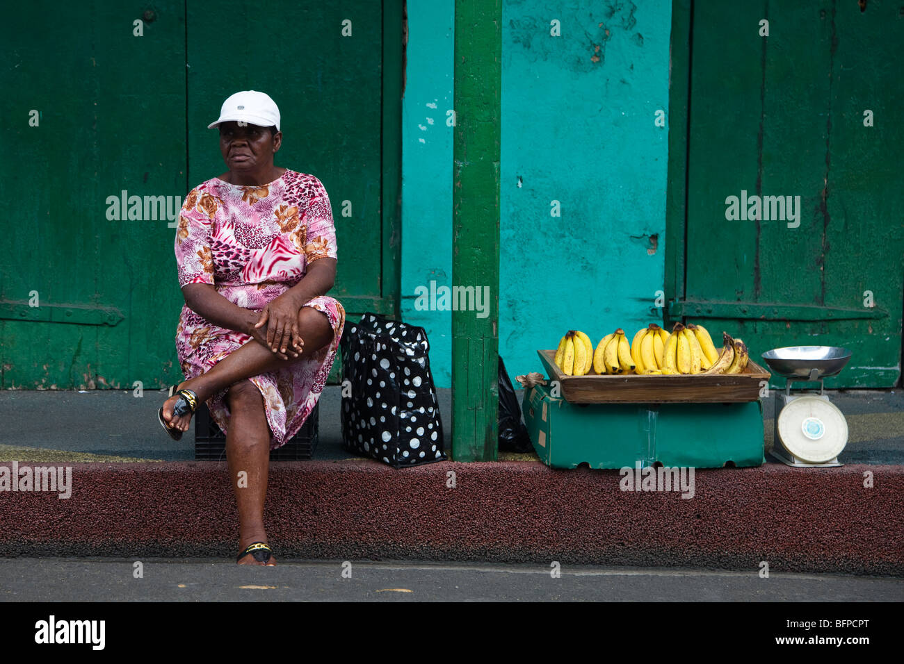 Black woman selling bananas from a pavement kerbside in St Johns, Antigua and Barbuda, West Indies Stock Photo