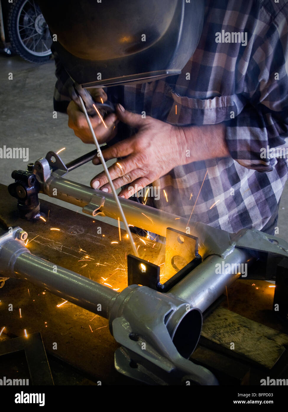 Moto mechanic welding in his shop in west Texas Stock Photo