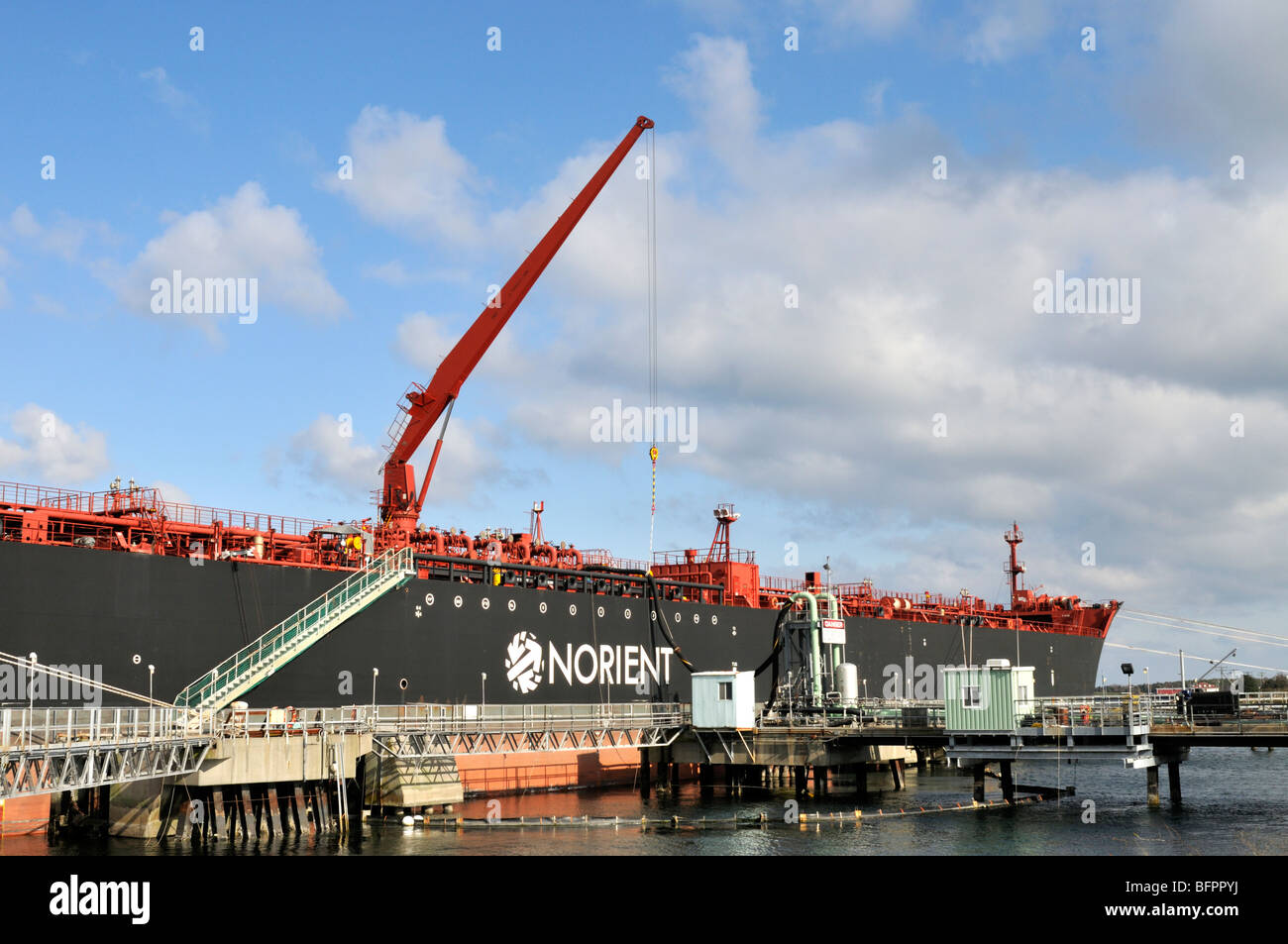 Fuel oil tanker offloading oil with a hose handling crane Stock Photo