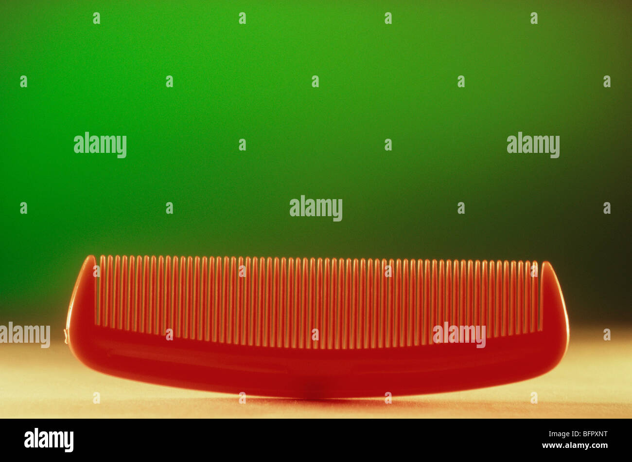 VHM 66692 : Concept ; plastic comb against green background Stock Photo