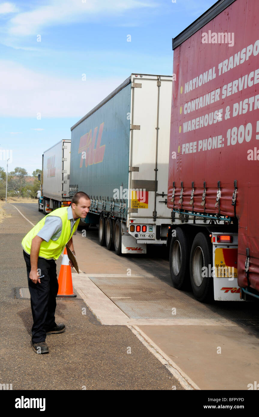 A 190-tonne road train being inspected and its total weight by a transport inspector at a weighing station in Alice Springs in the Northern Territory, Stock Photo