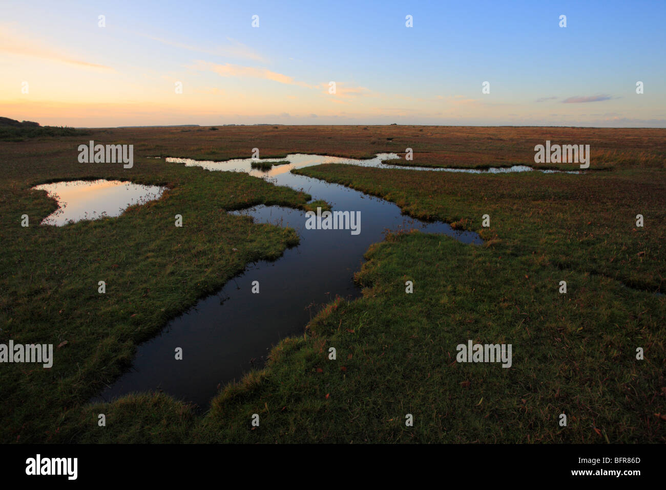 Stiffkey saltmarshes with the evening sky reflected in pools of water. Stock Photo