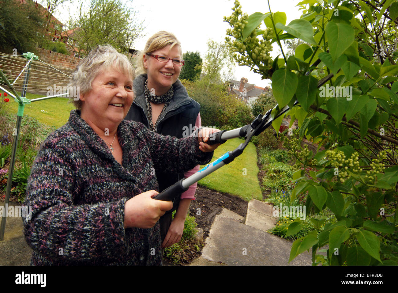 A resident and Support Worker trim the hedge of the Housing Association garden for people with mental health problems, York. Stock Photo