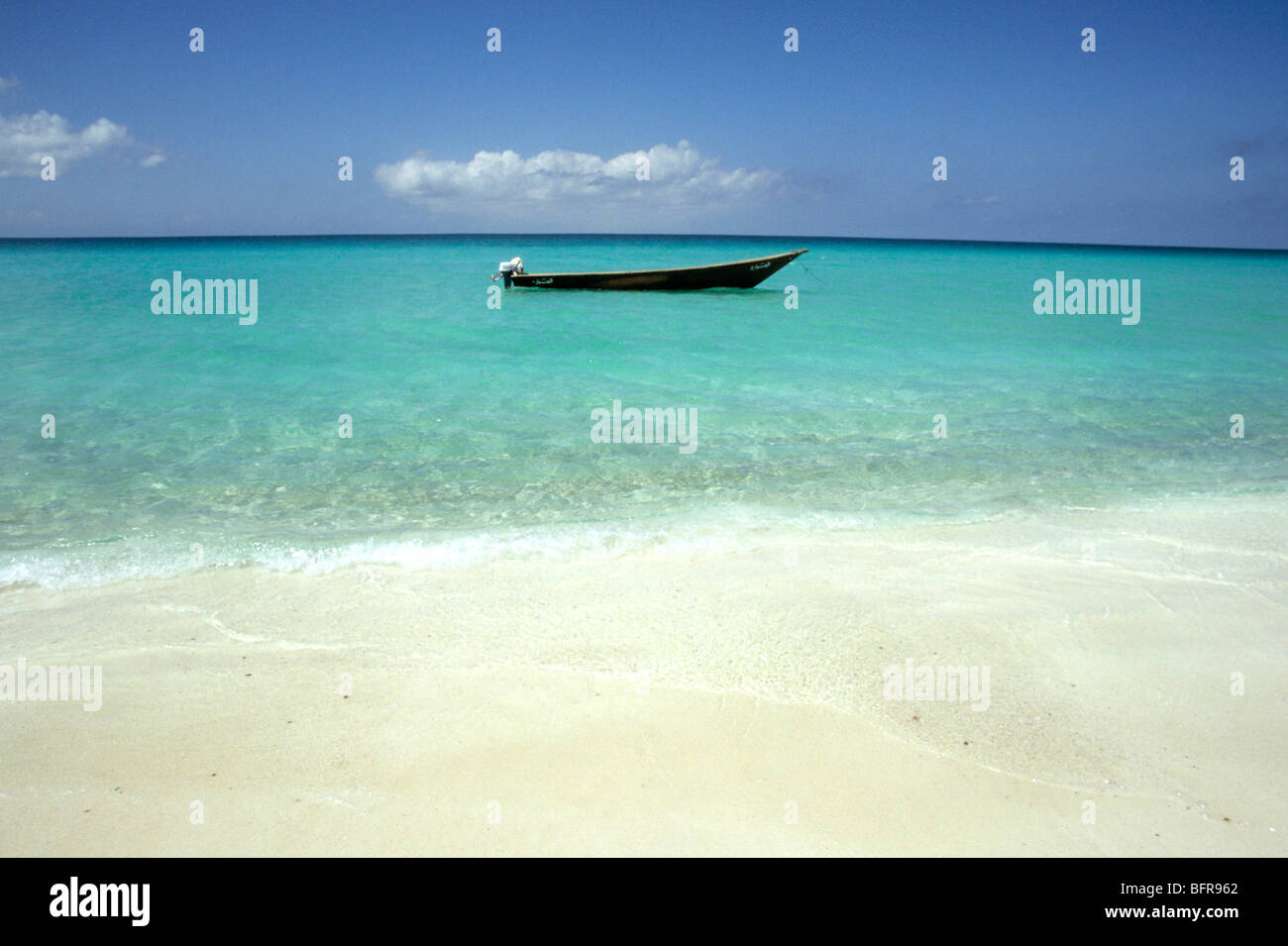 White sand beach and a fishing boat in shallow water Stock Photo - Alamy