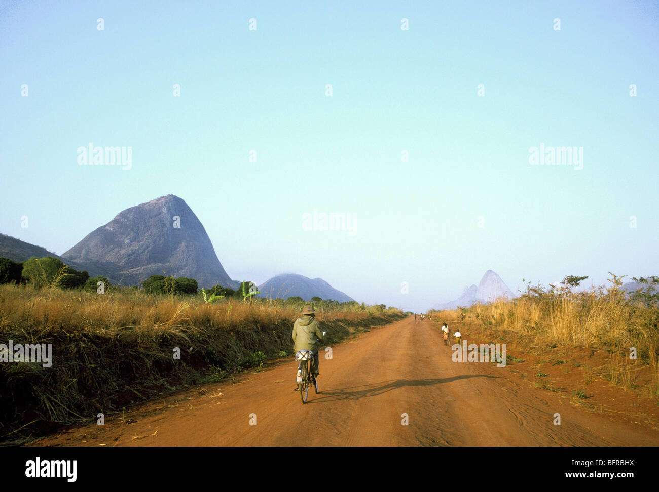 Man cycling and people walking on the road to Cuamba Stock Photo - Alamy