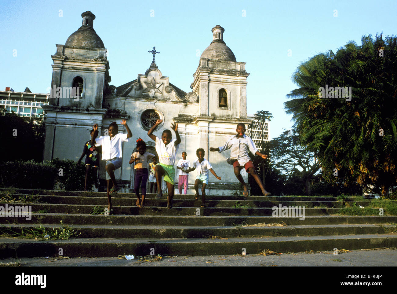 Children running and jumping down the steps in front of the Catholic cathedral Stock Photo