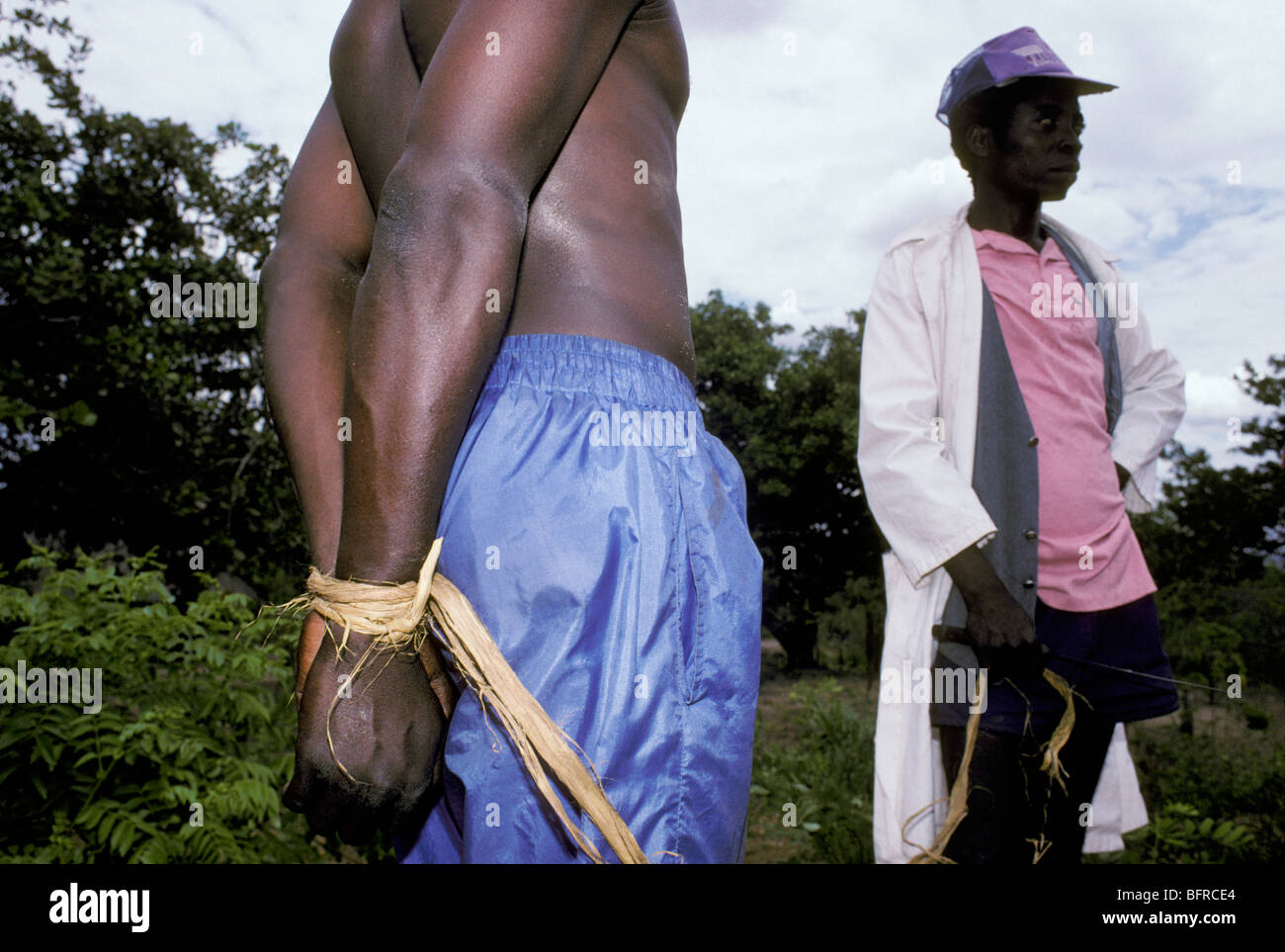 Man accused of bicycle theft with hands tied up with rope being led to police station north of Macomia Stock Photo