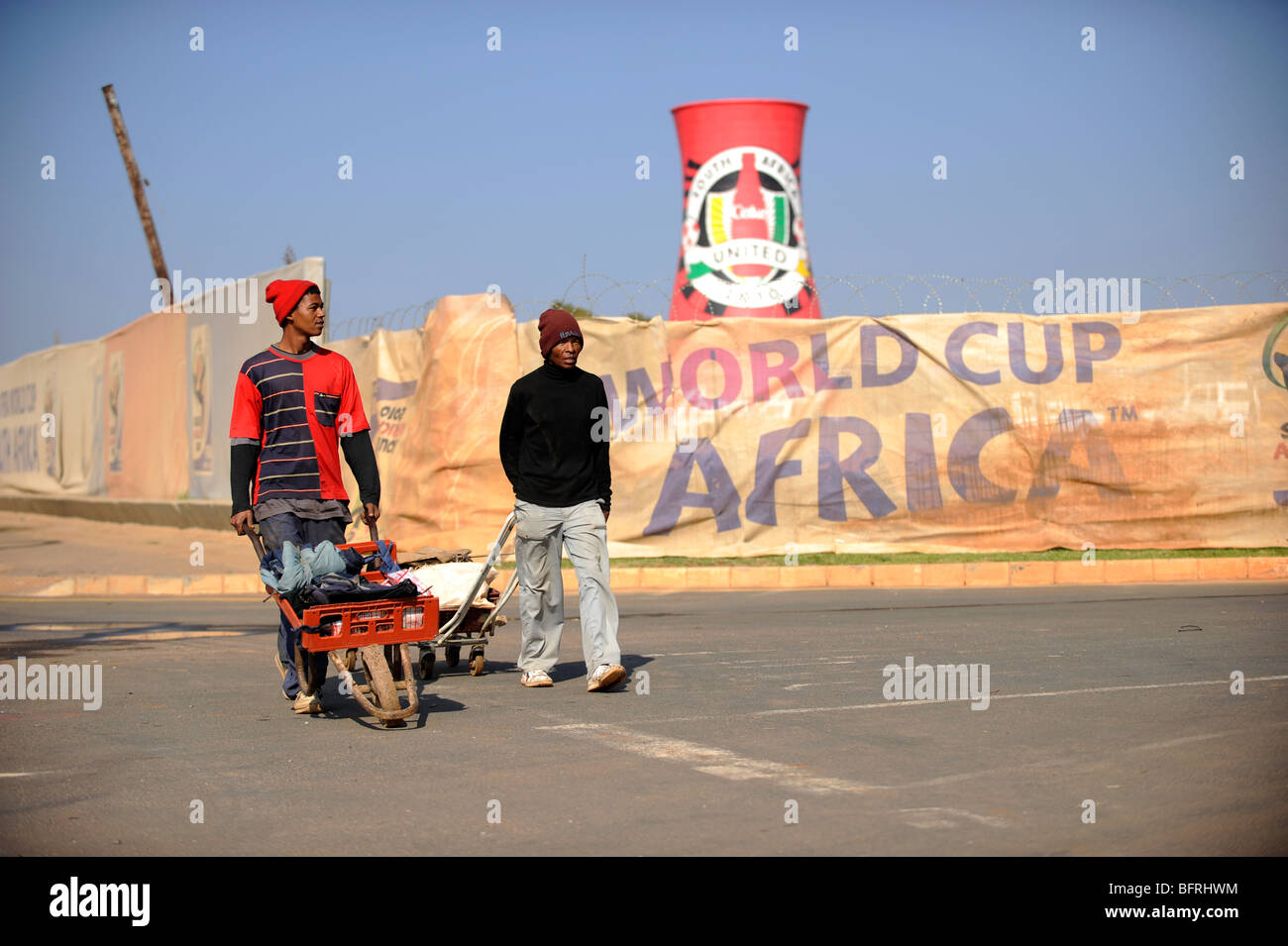 Two workmen pass Soccer City Stadium in South Africa - venue for 2010 FIFA World Cup in Johannesburg, South Africa Stock Photo