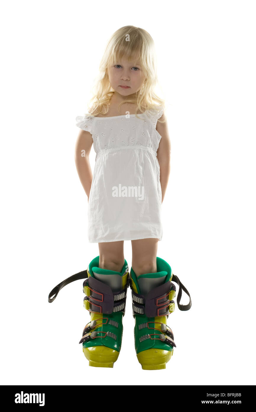 little girl in a white dress and big ski boots holds hands behind the back, isolated on white Stock Photo