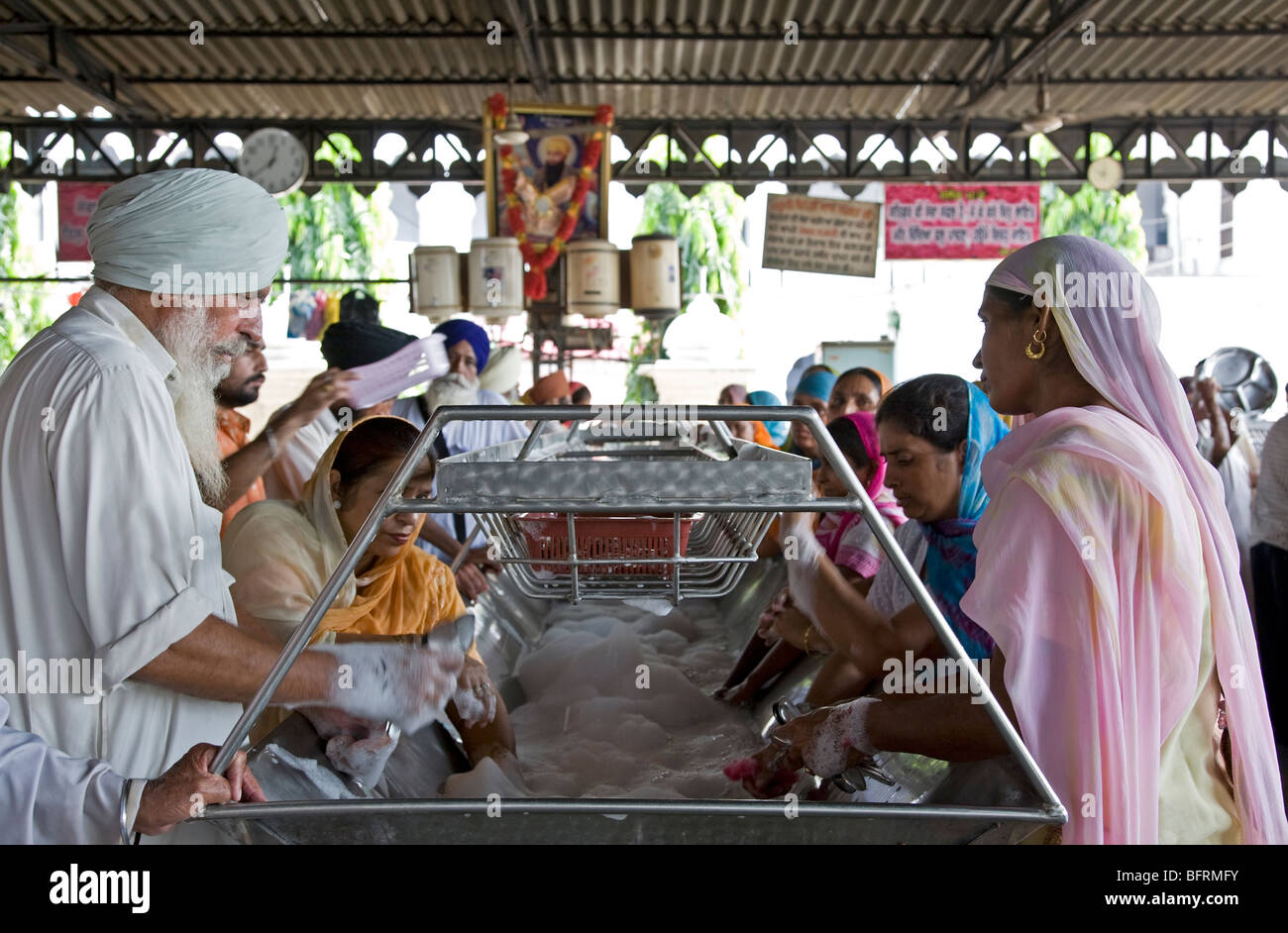 Sikh pilgrims washing the dishes. The Golden Temple kitchen. Amritsar. Punjab. India Stock Photo