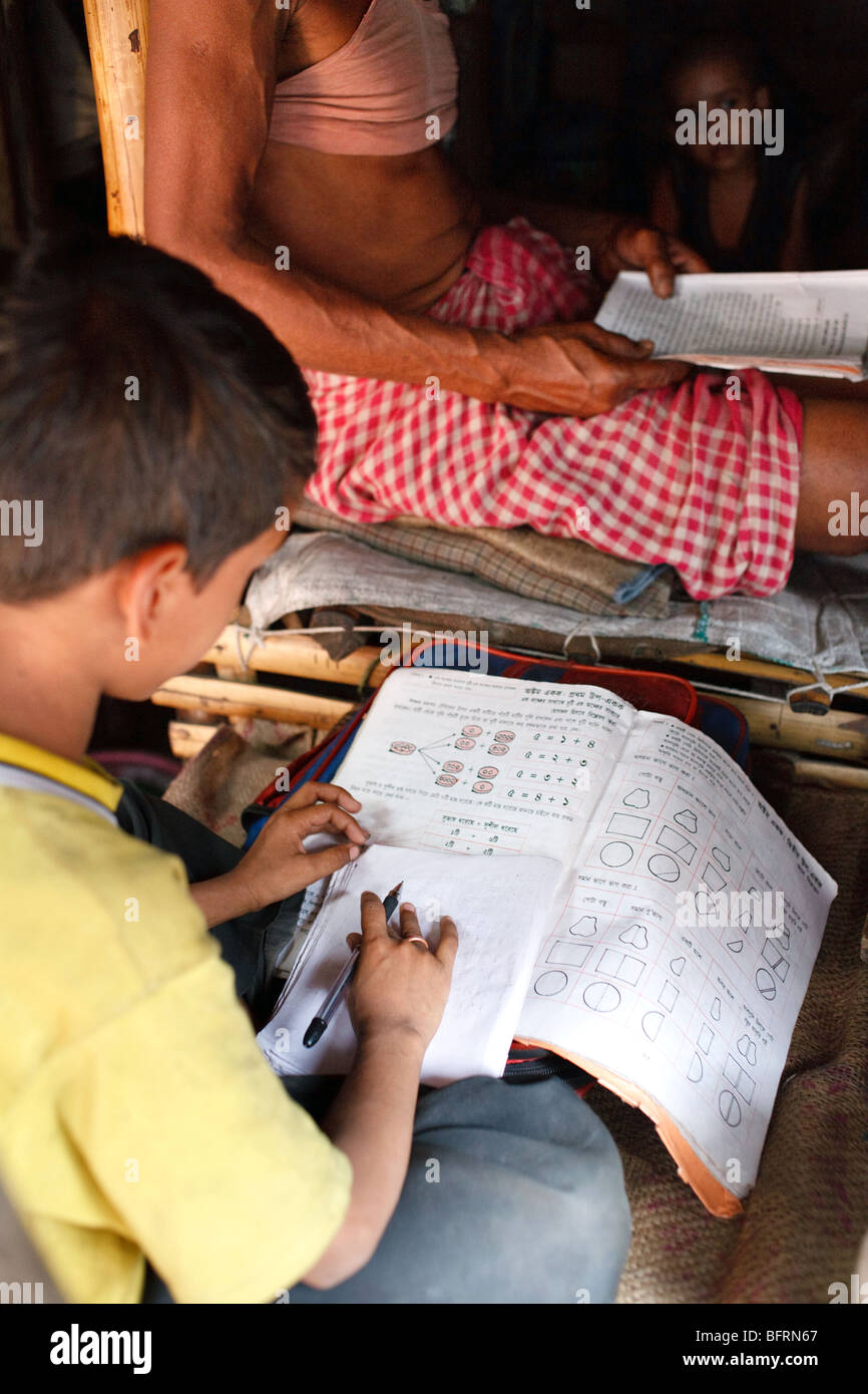 a boy does his homework in his home in one of the slums in Kolkata, India Stock Photo