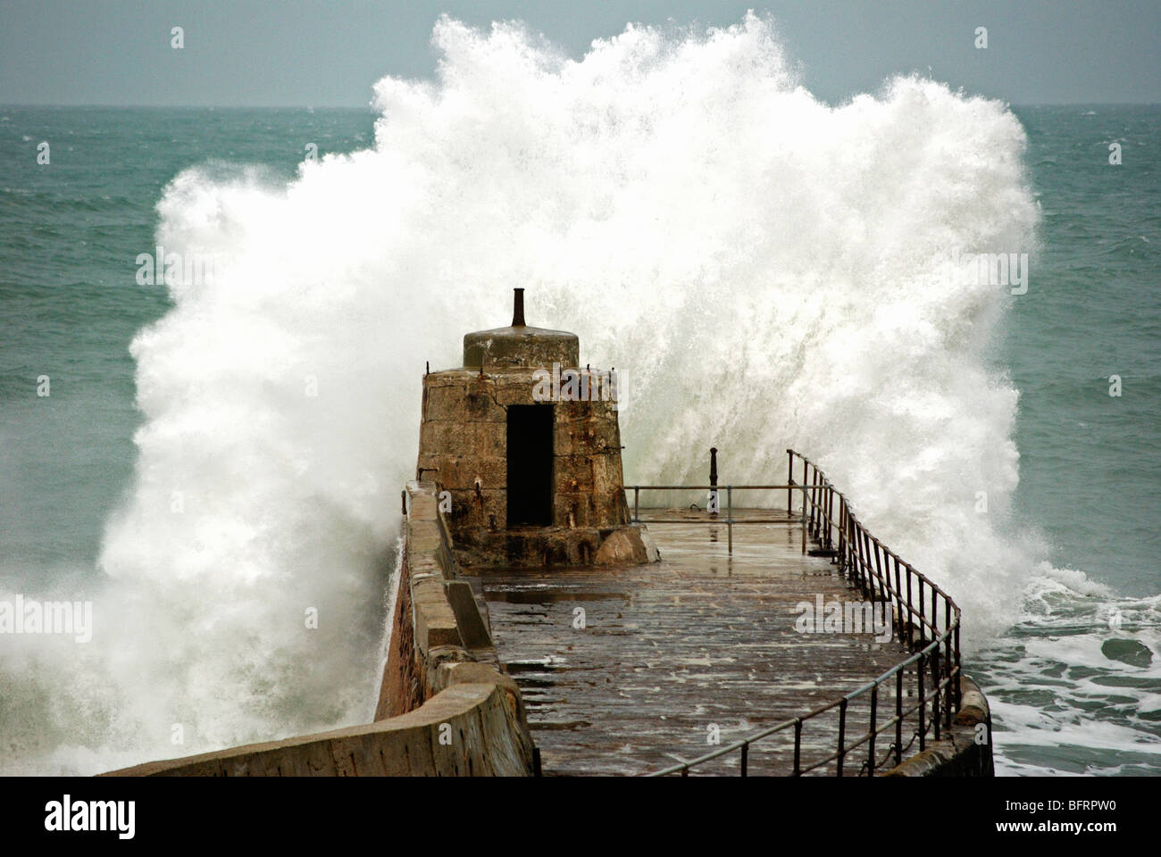 waves breaking over the old pier at portreath in cornwall, uk Stock Photo