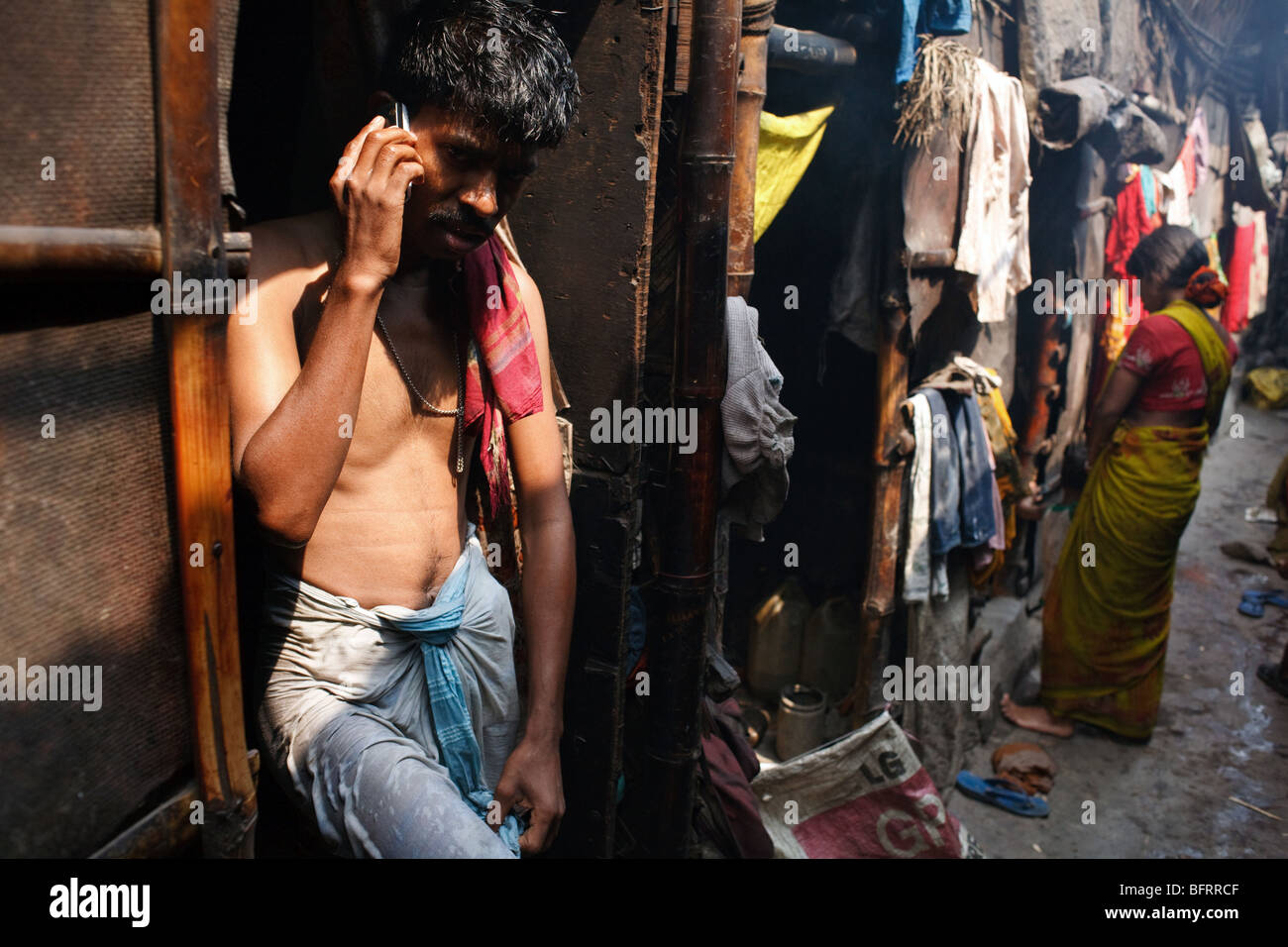 A man talks on his mobile phone in a slum in Kolkata, India Stock Photo