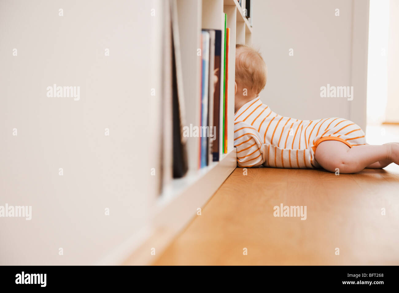 Baby Lying on Floor Looking in Bookshelf Stock Photo - Alamy
