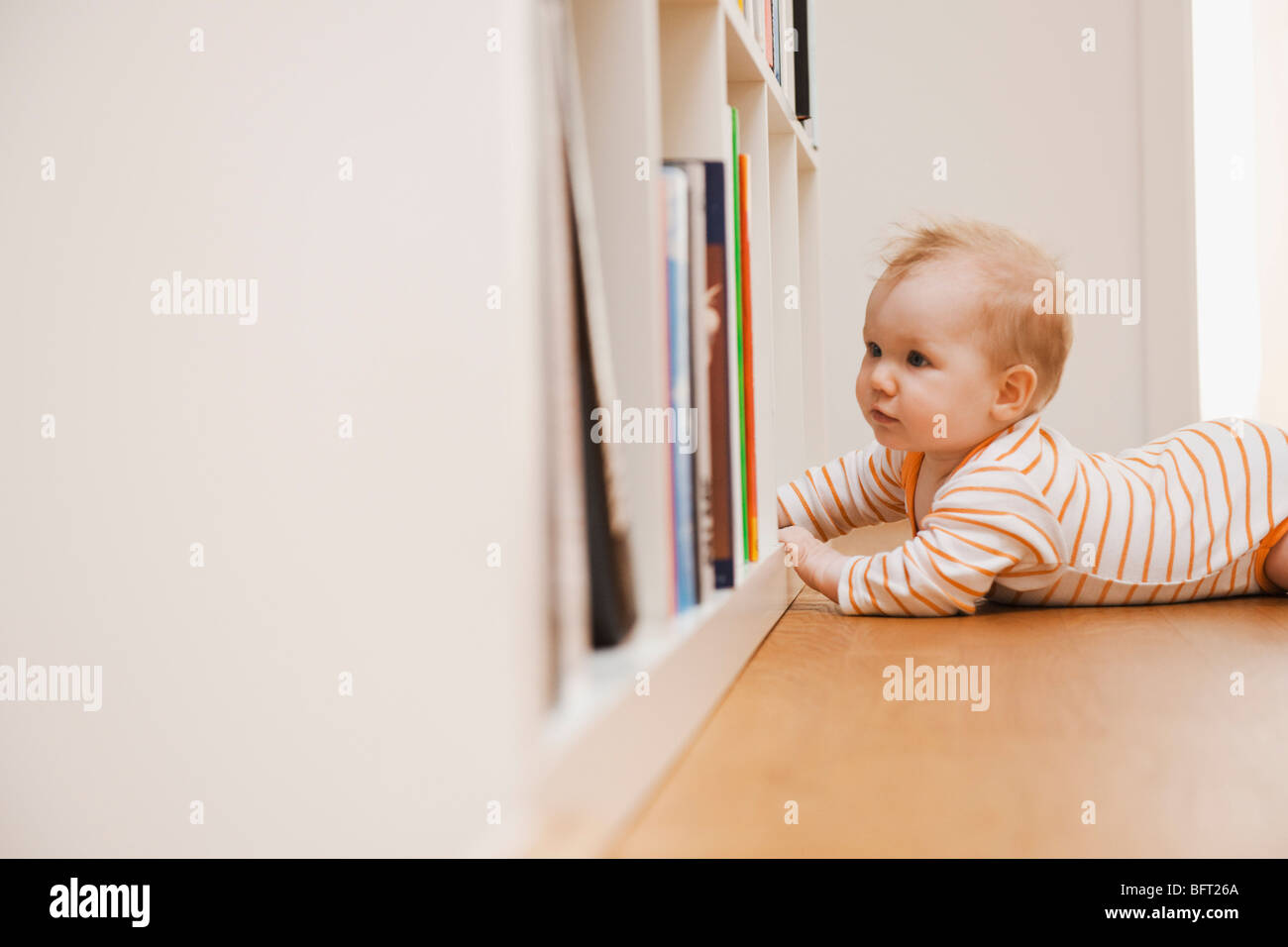 Baby Lying on Floor Looking in Bookshelf Stock Photo - Alamy