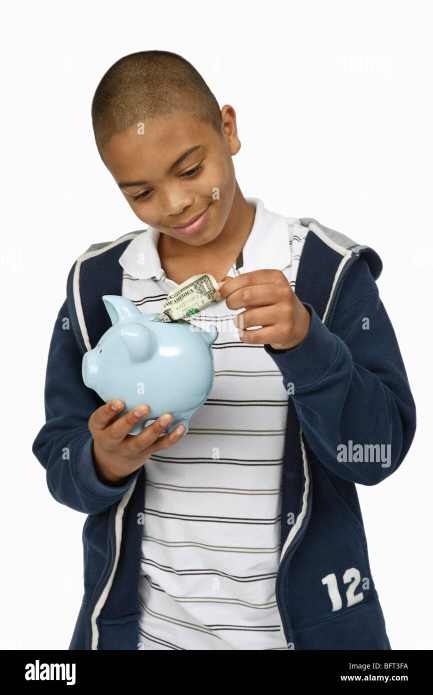 Boy Putting Money in Piggy Bank Stock Photo - Alamy