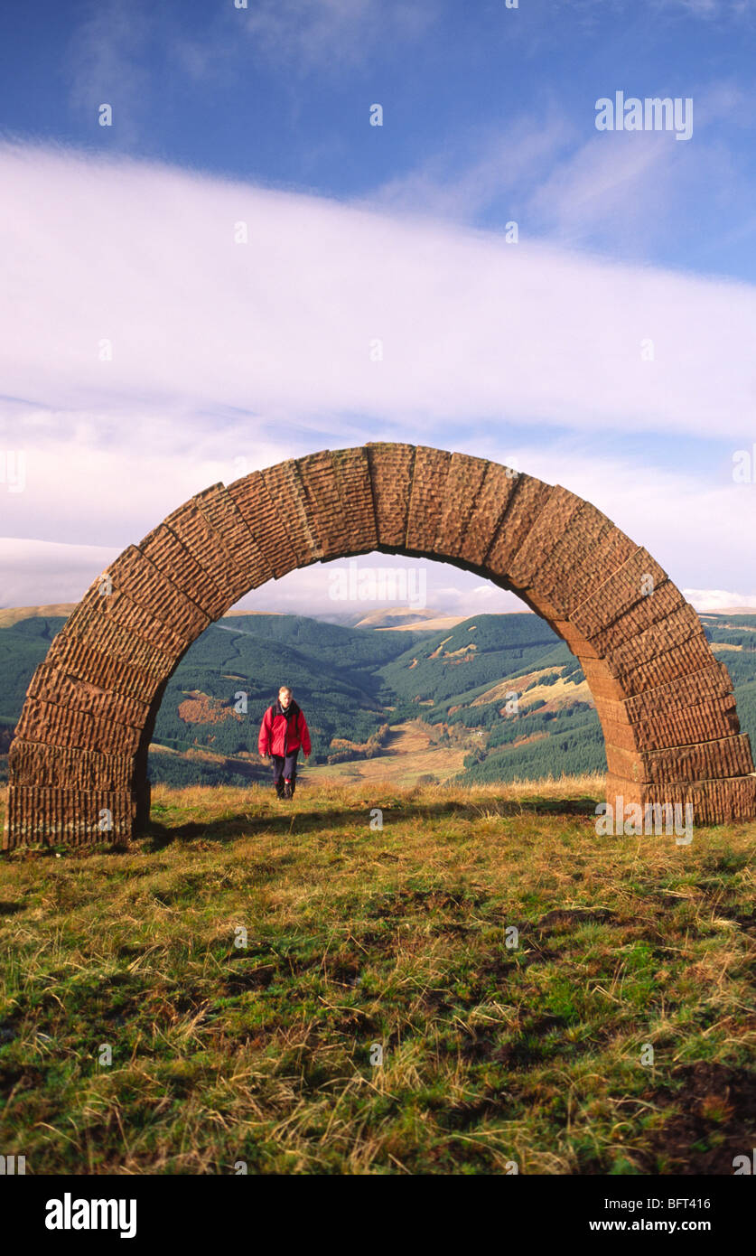 Hill walker climbing out of Dalwhat Glen and under Andy Goldsworhy's Striding Arch sculpture near Moniaive Scotland UK Stock Photo