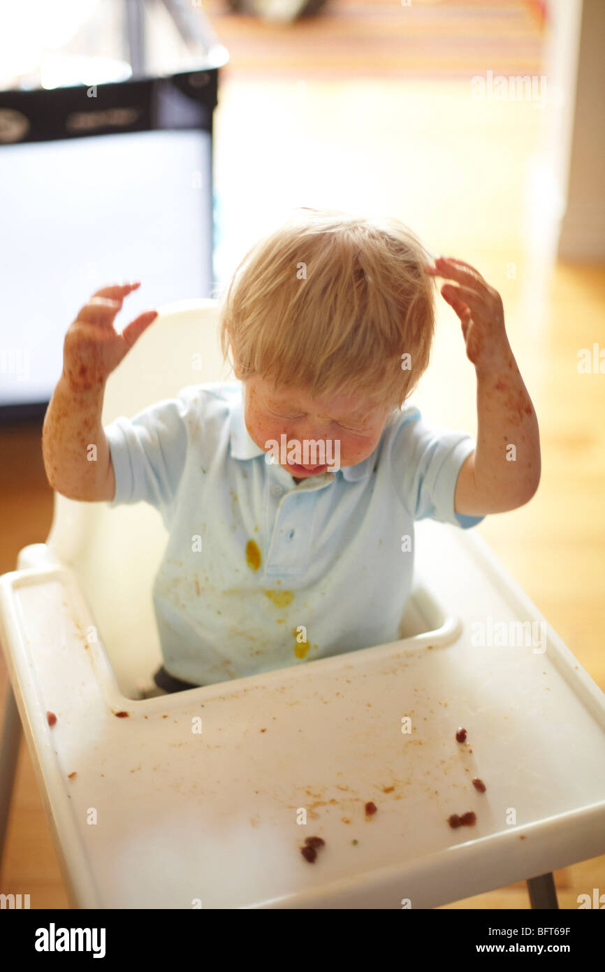 Baby Boy in High Chair, Making a mess With His Food Stock Photo