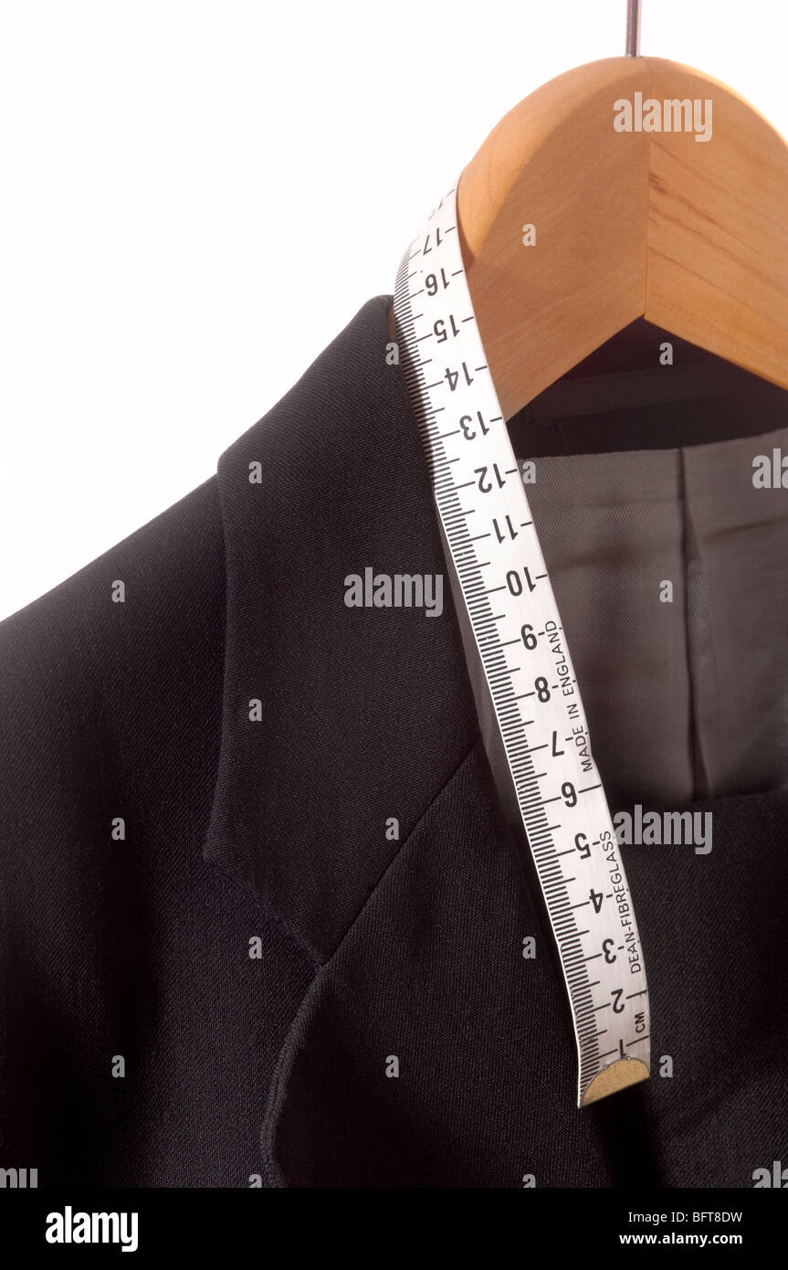 Closeup of the collar and lapel of a black tailored jacket hanging on a wooden coat hanger with tape measure Stock Photo