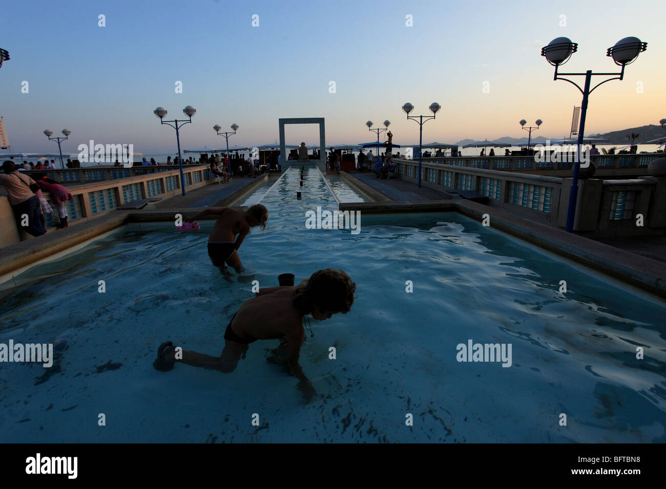 The mediterranean coastal city of Juan les Pins near Cannes and the fountain where kids are playing inside at night. Stock Photo