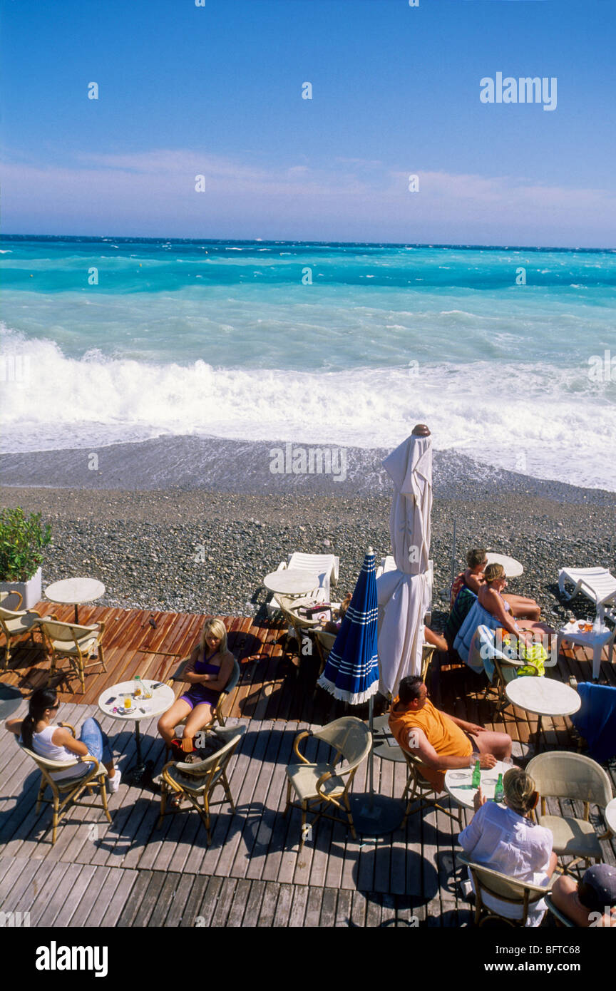 People relaxing in front of a rough sea on a beach of Nice Stock Photo