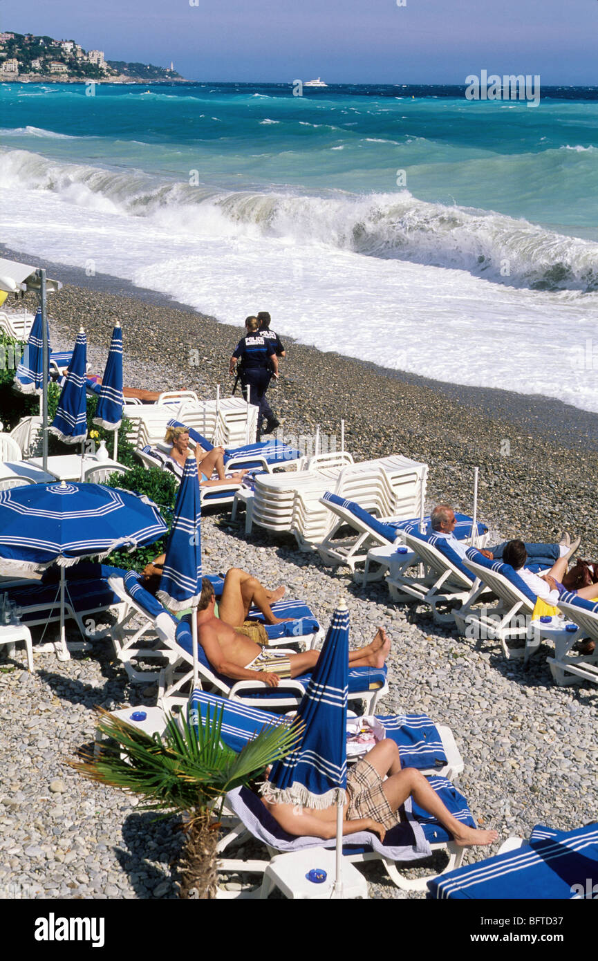 People relaxing in lounge chair facing a rough sea Stock Photo