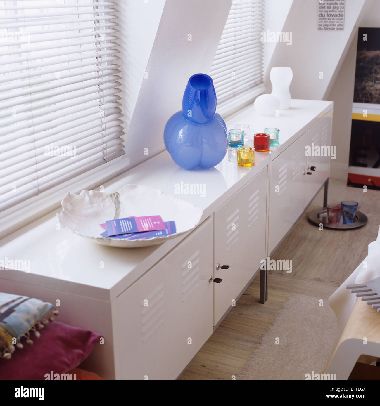 Modern designer storage cabinet beneath windows with blinds in a contemporary apartment/ flat. Stock Photo
