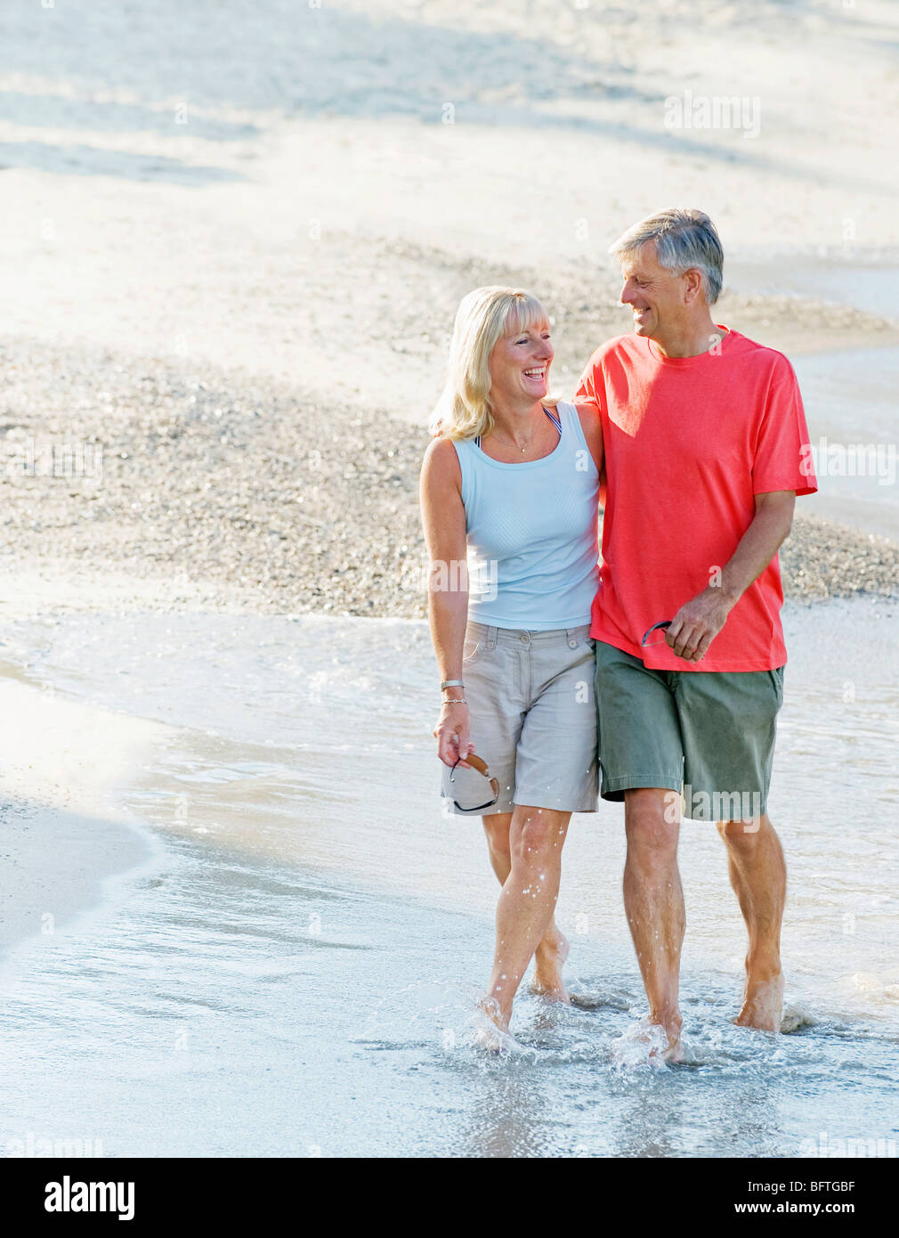 Couple walking along beach shore hires stock photography and images