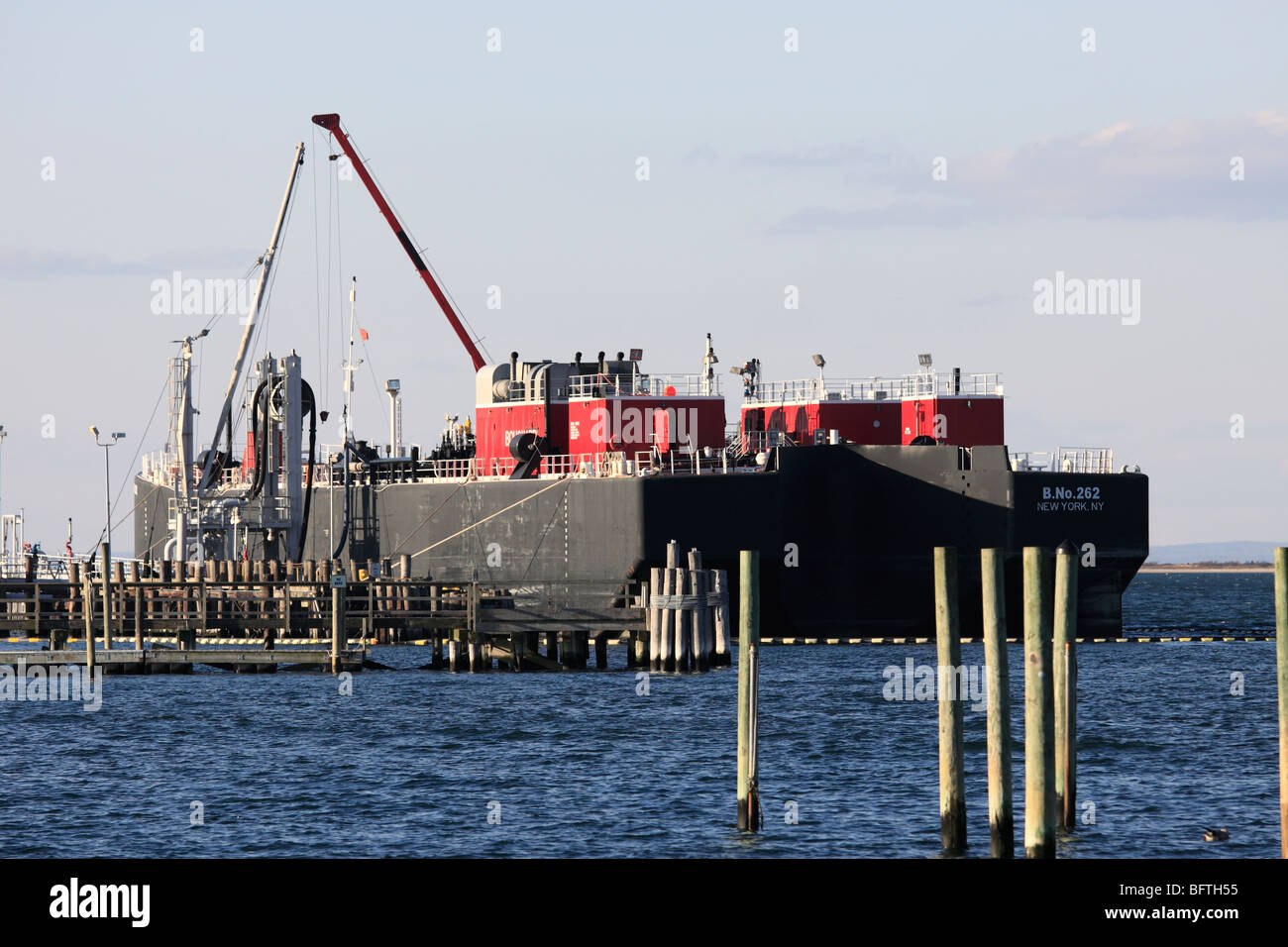 A double hulled oil tank barge unloads its cargo of of oil at power generating plant, Port Jefferson, Long Island, NY Stock Photo