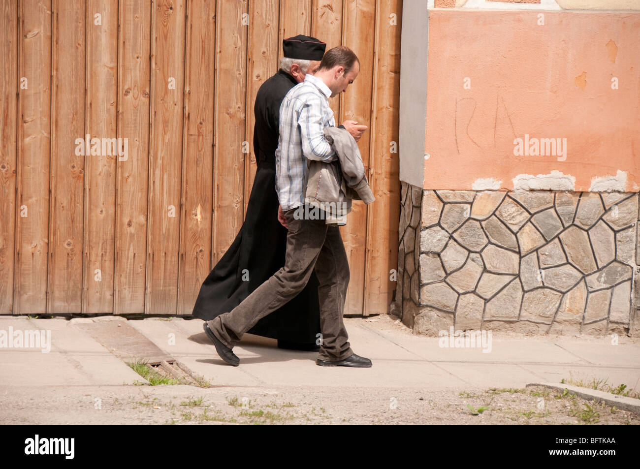 Romanian and Orthodox Catholic Priest walking along road in Apoldu de Sus Romania Eastern Europe Stock Photo