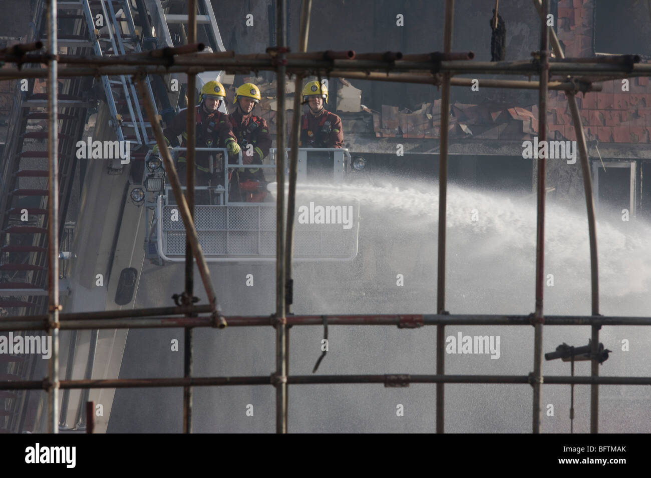 London Fire fighters dampen down smouldering remains from a Simon Snorkel platform after an