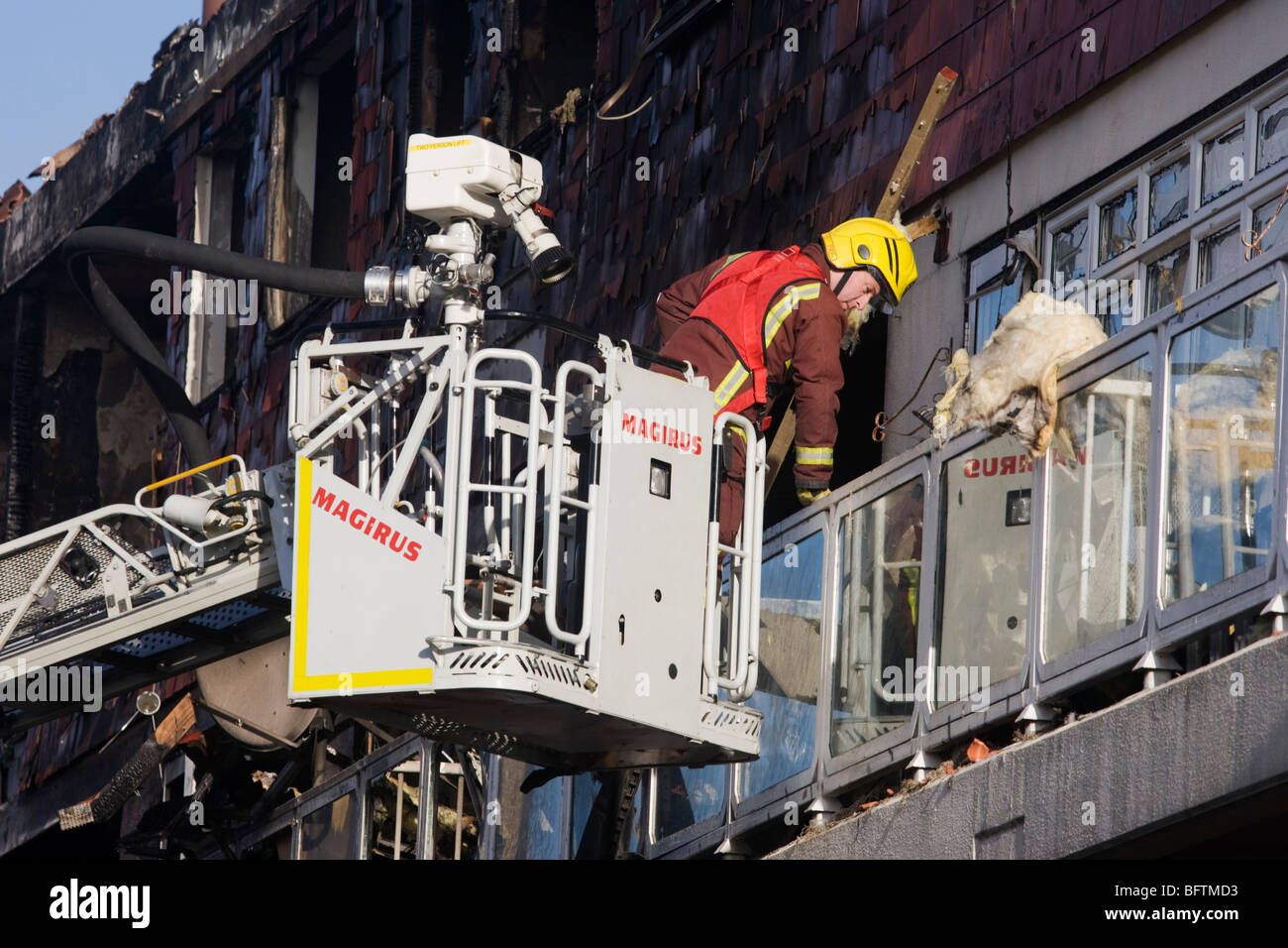 On a Simon Snorkel platform, a fire fighter makes an inspection of properties after an inner-city estate fire in south London. Stock Photo