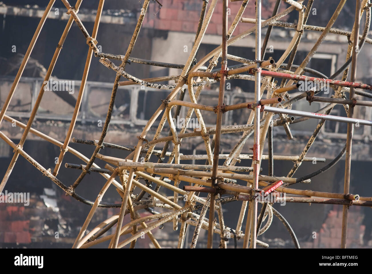 Twisted scaffolding amid smouldering remains of a construction site after an inner-city estate fire in south London. Stock Photo