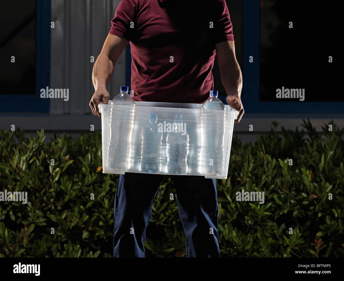 man carrying box of water at night Stock Photo