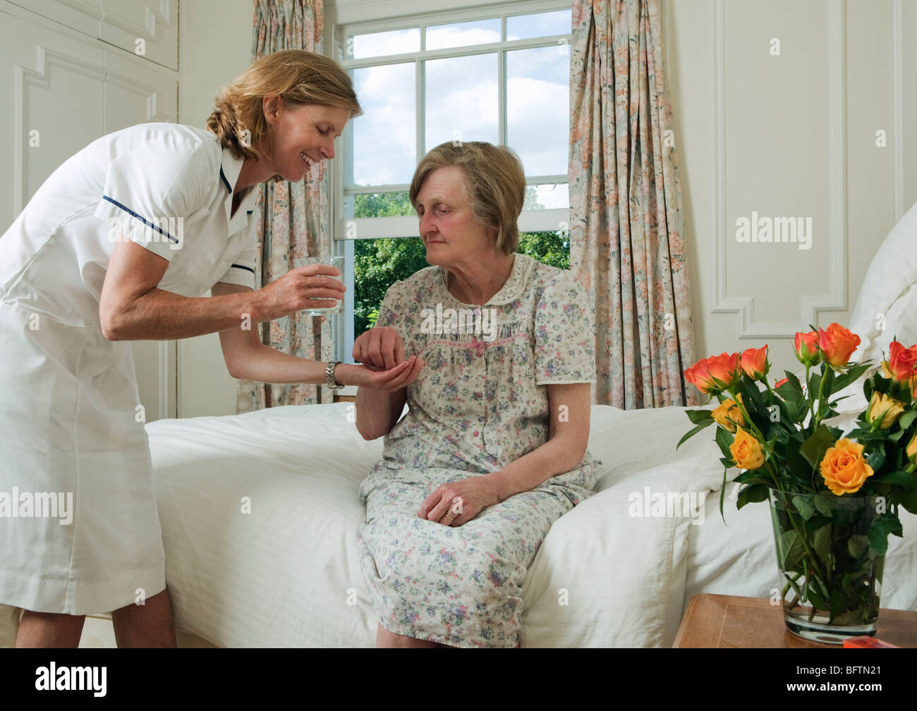 Elderly woman taking pill from nurse Stock Photo