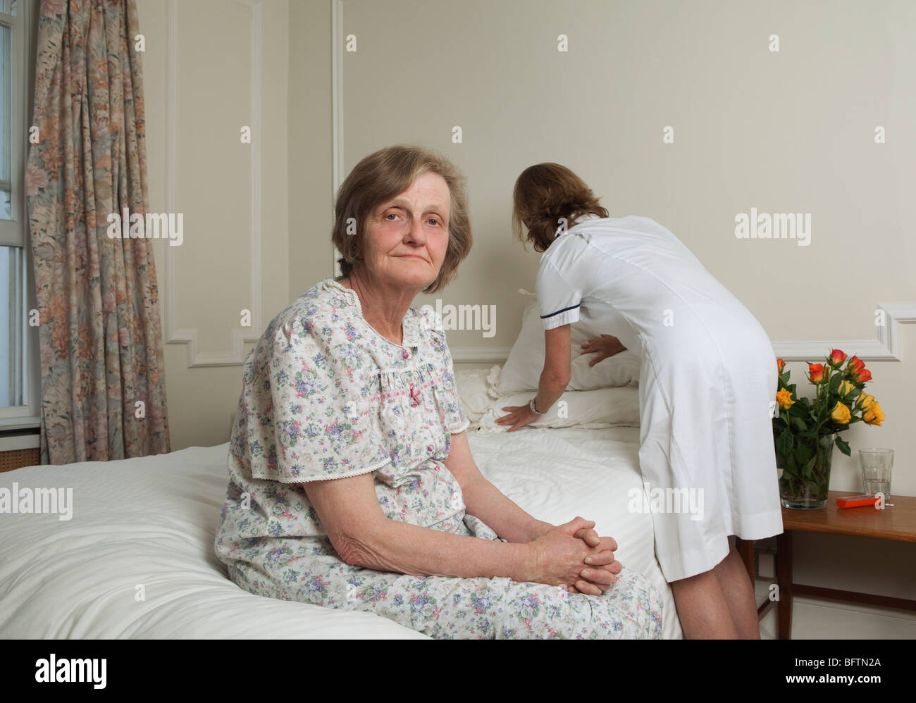 Nurse making bed for elderly woman Stock Photo Alamy