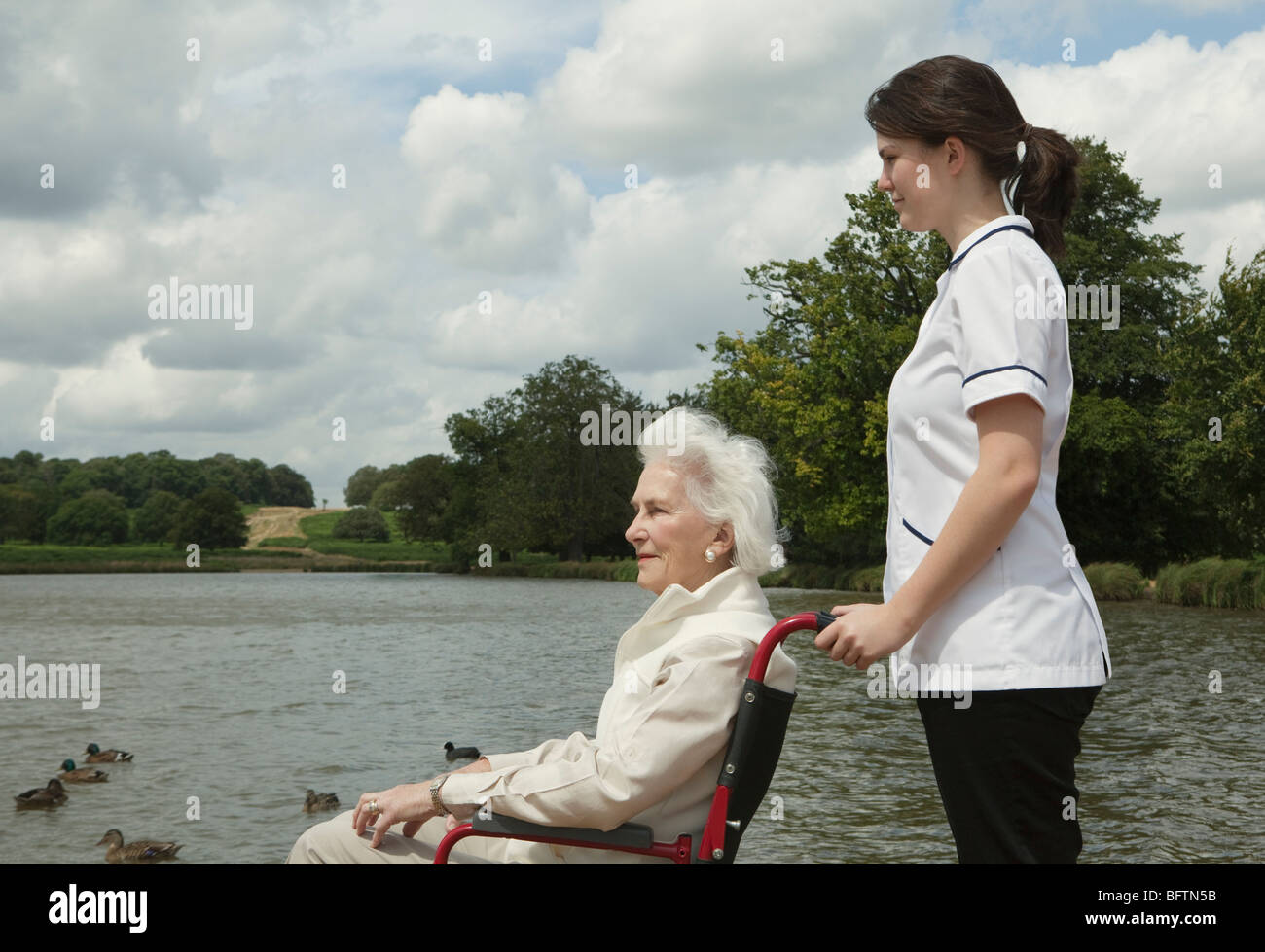 Elderly woman in wheelchair with nurse Stock Photo