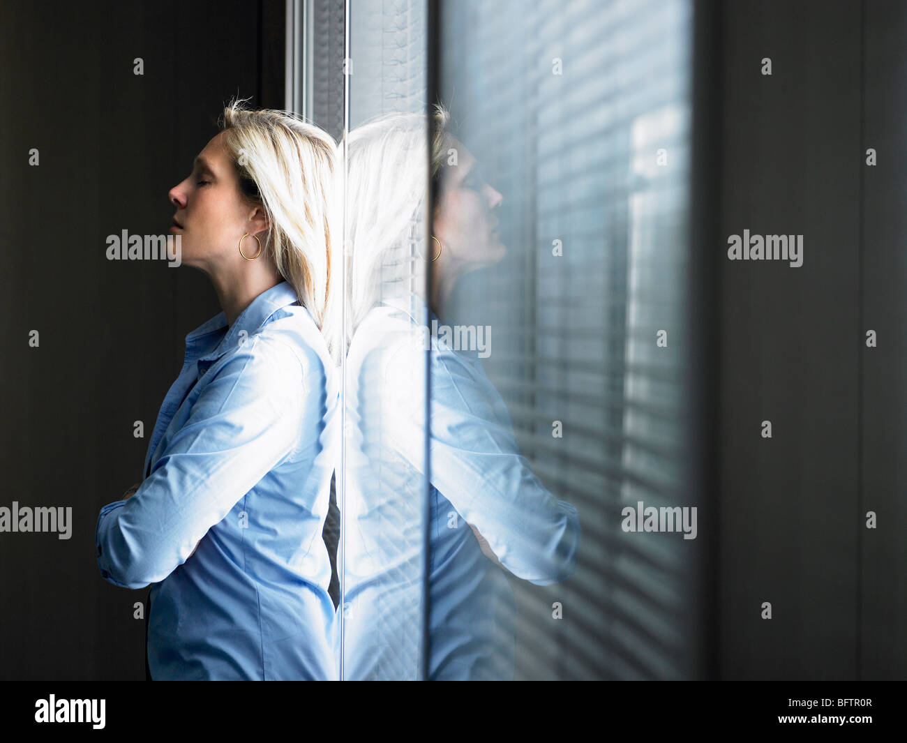 Woman against window, thinking Stock Photo