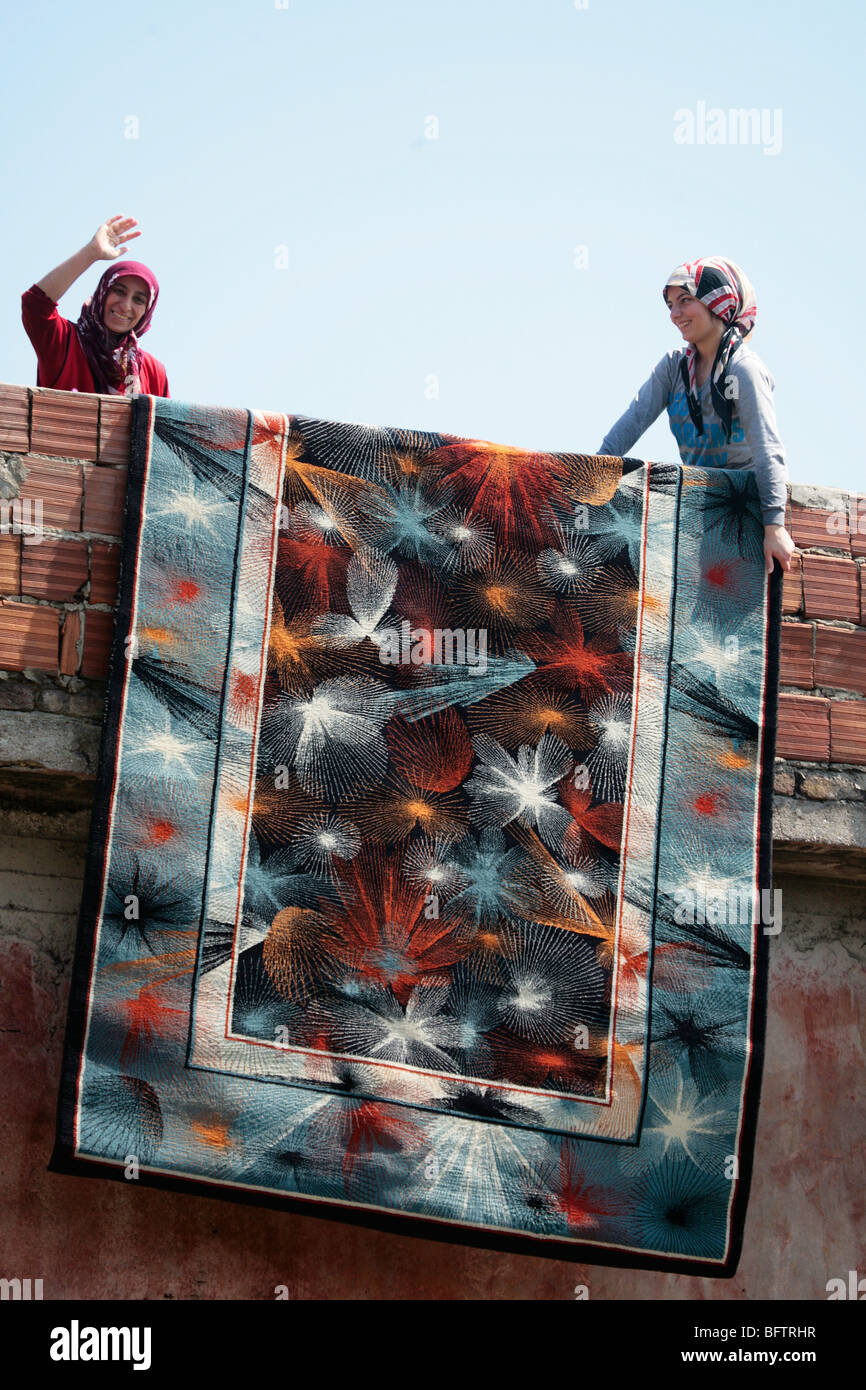 Women hanging a carpet out to dry in Istanbul's traditional Muslim Fatih District Stock Photo