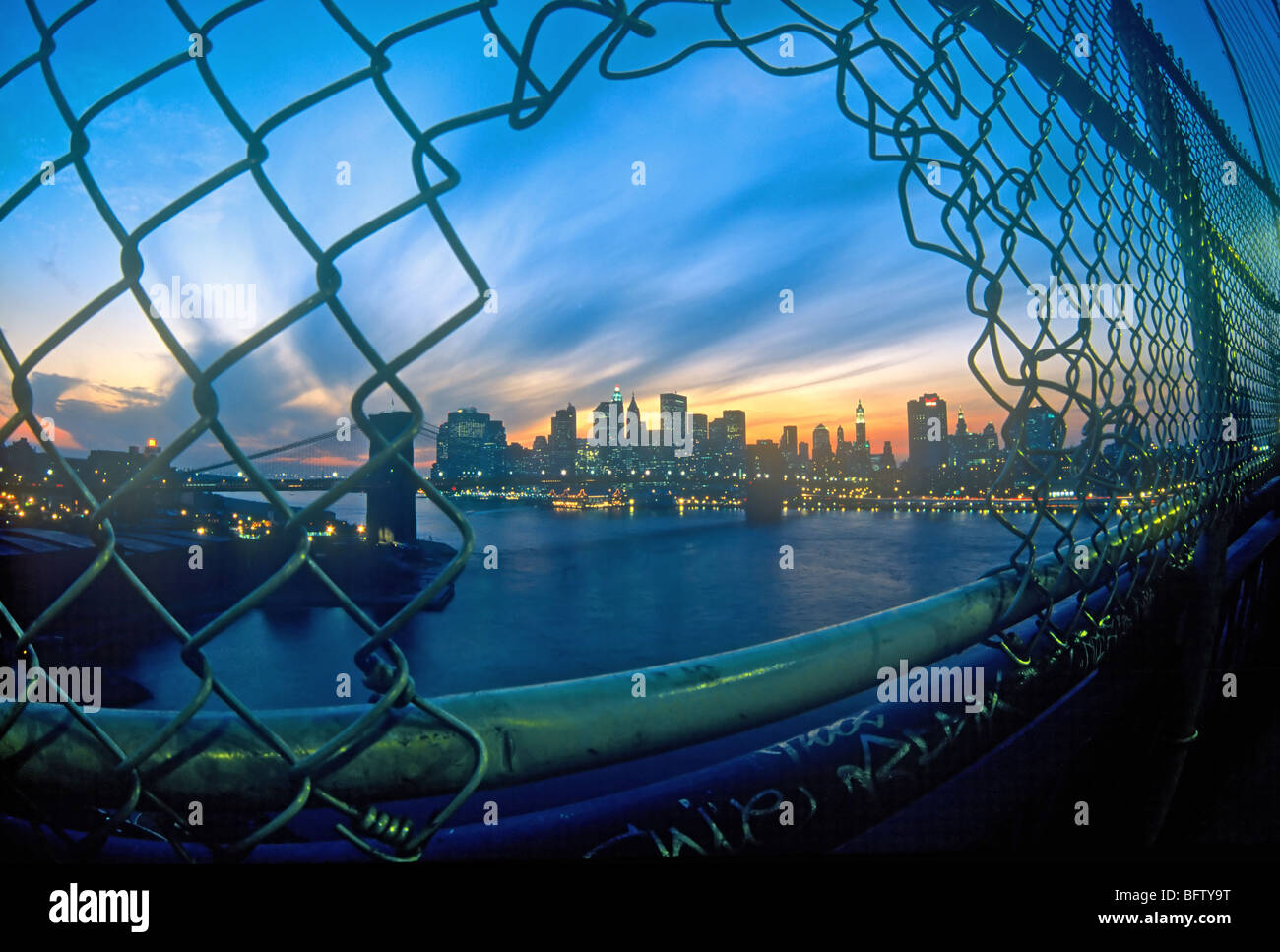 New York City skyline as seen through a hole in the fence on the Manhattan bridge Stock Photo
